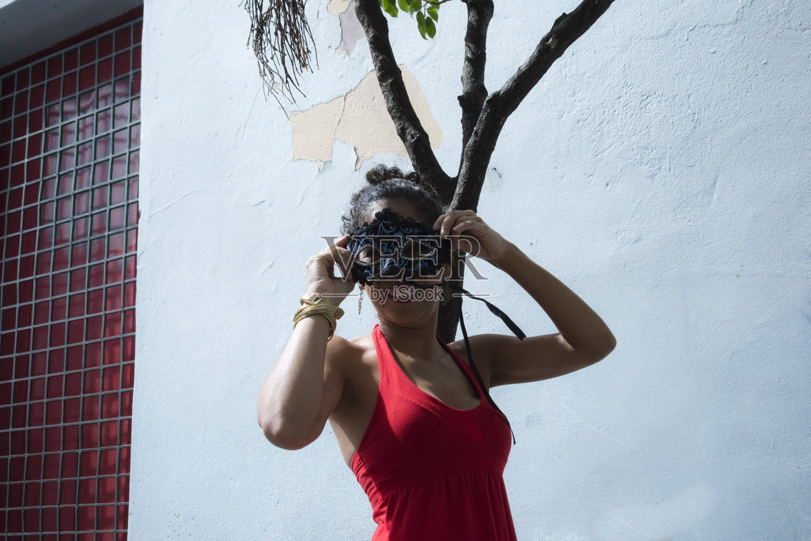 一个戴着狂欢节面具的女人的肖像，靠在淡蓝色的墙上。照片摄影图片