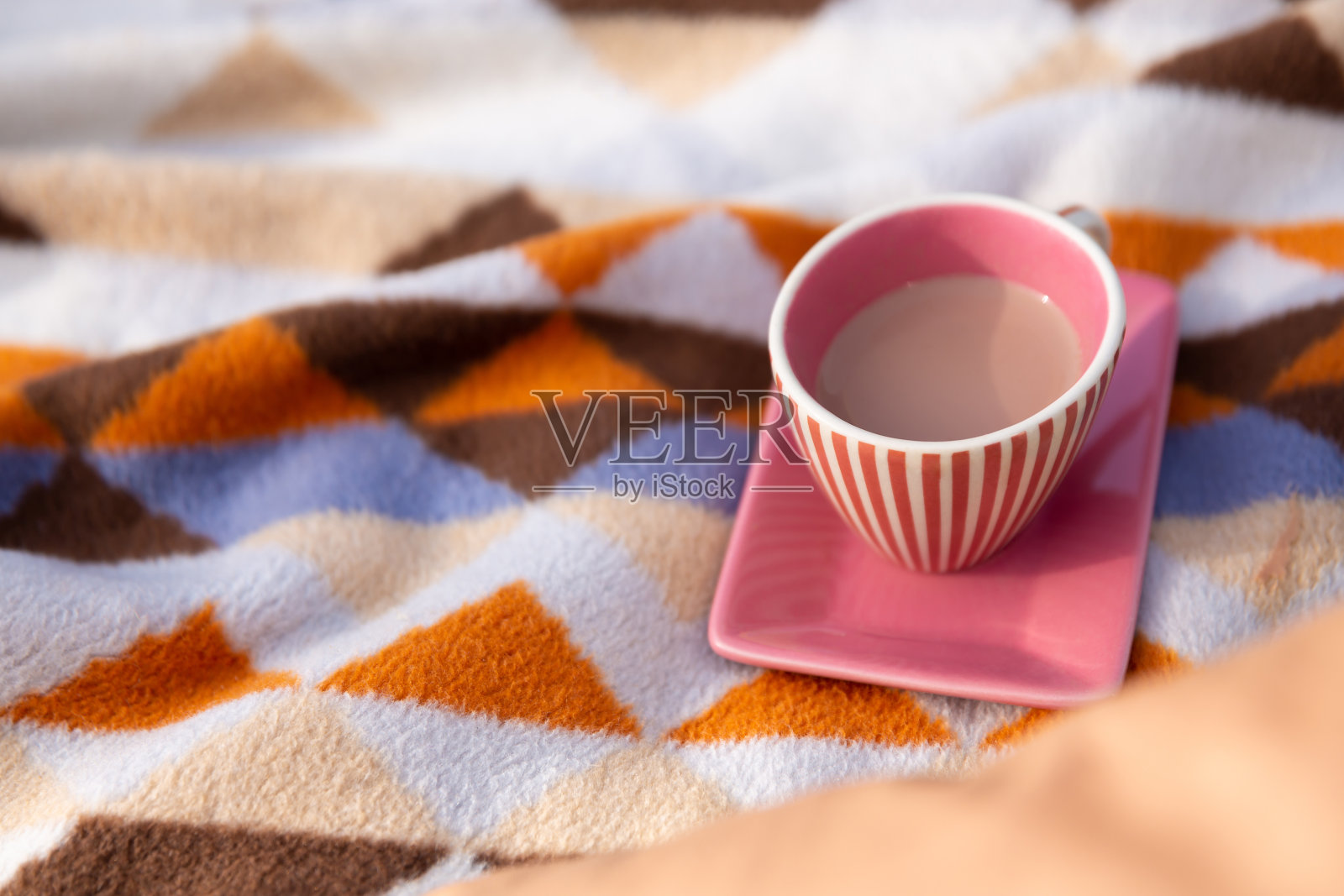 装有可可或咖啡热饮的杯子放在格子上照片摄影图片