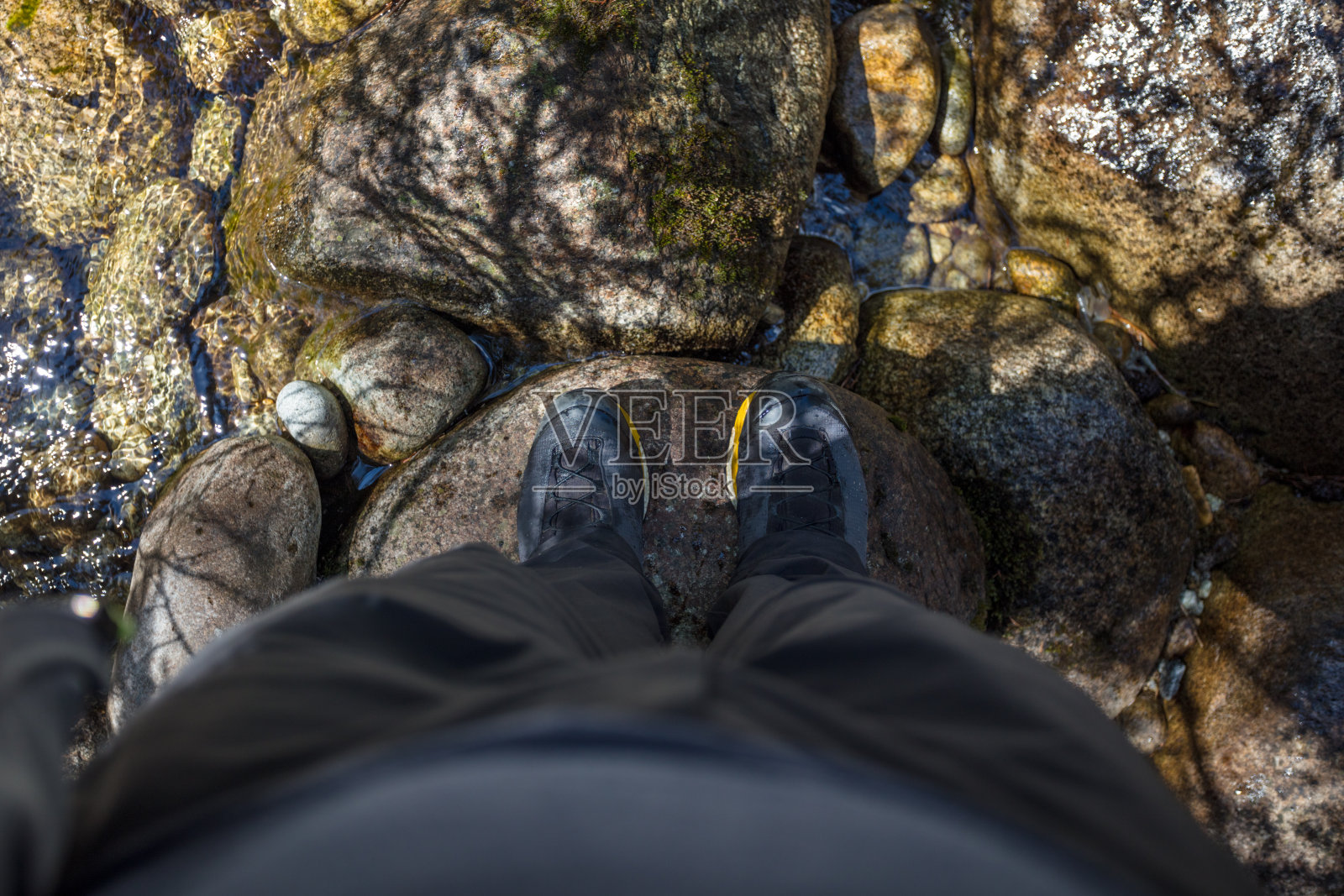 穿着登山靴的男人们站在山涧的石头上照片摄影图片