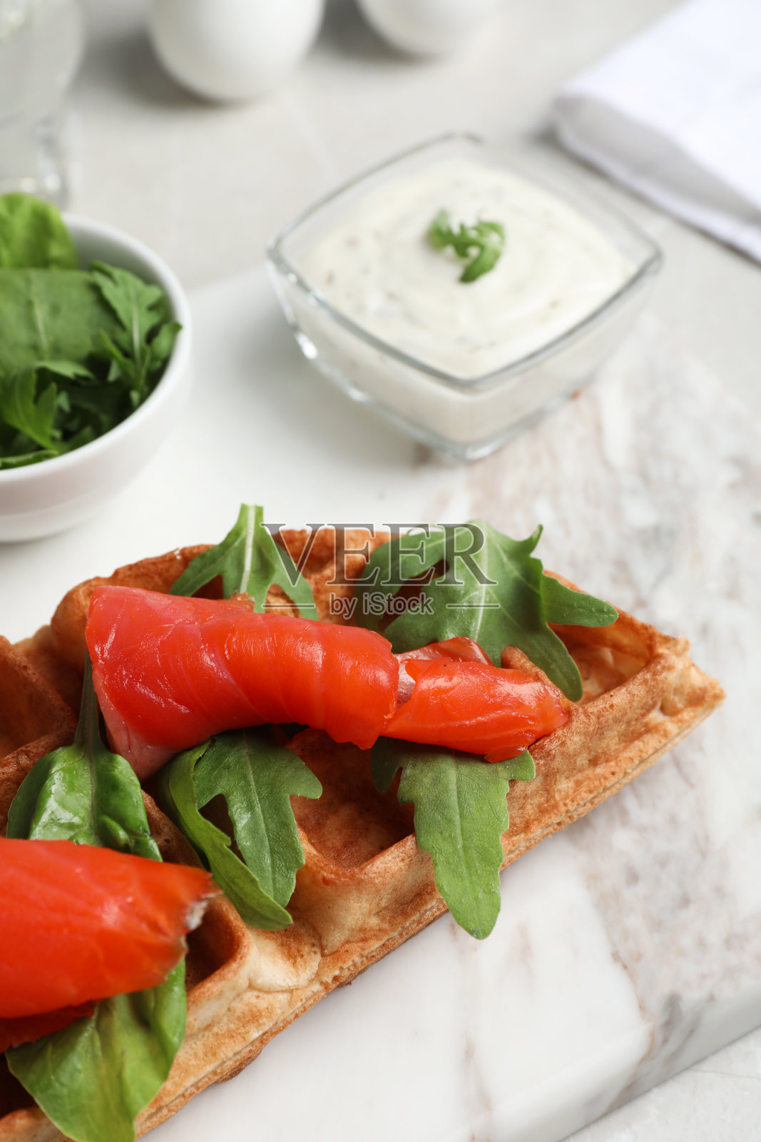 新鲜的比利时华夫饼配鲑鱼和芝麻菜在白色的桌子上，特写照片摄影图片