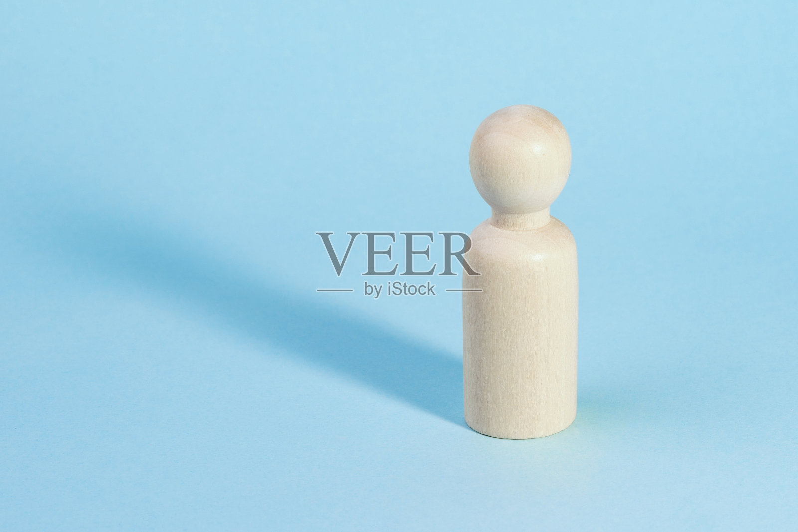 一个木雕孤零零地站在蓝色的背景上。照片摄影图片