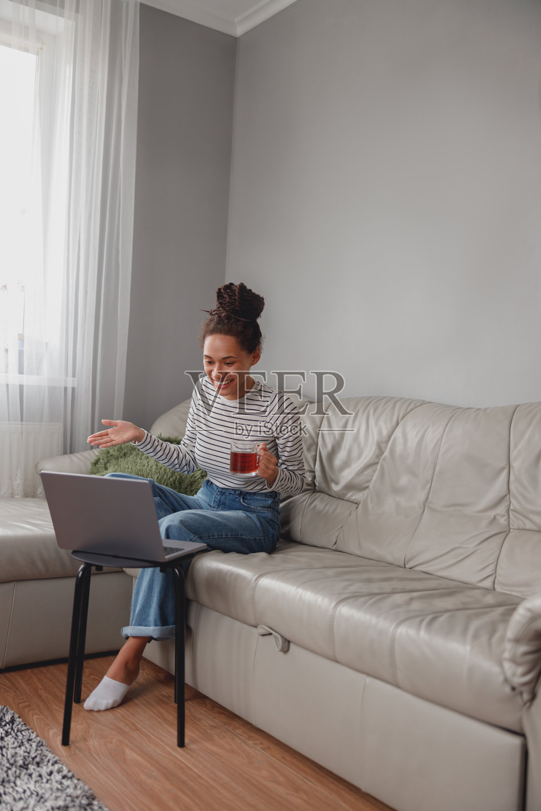 快乐的美女有说有笑，视频聊天，喝茶。摄像头的电话。照片摄影图片