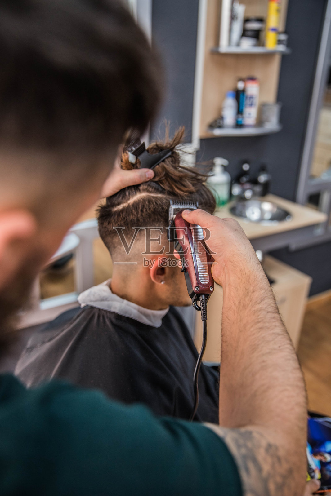 理发师用他的修剪器给年轻的顾客理发照片摄影图片