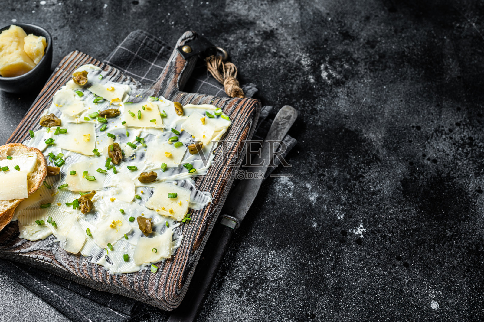 黄油板配香草，柠檬皮，酸豆，帕玛森奶酪和海盐，黄油板。黑色背景。前视图。本空间照片摄影图片