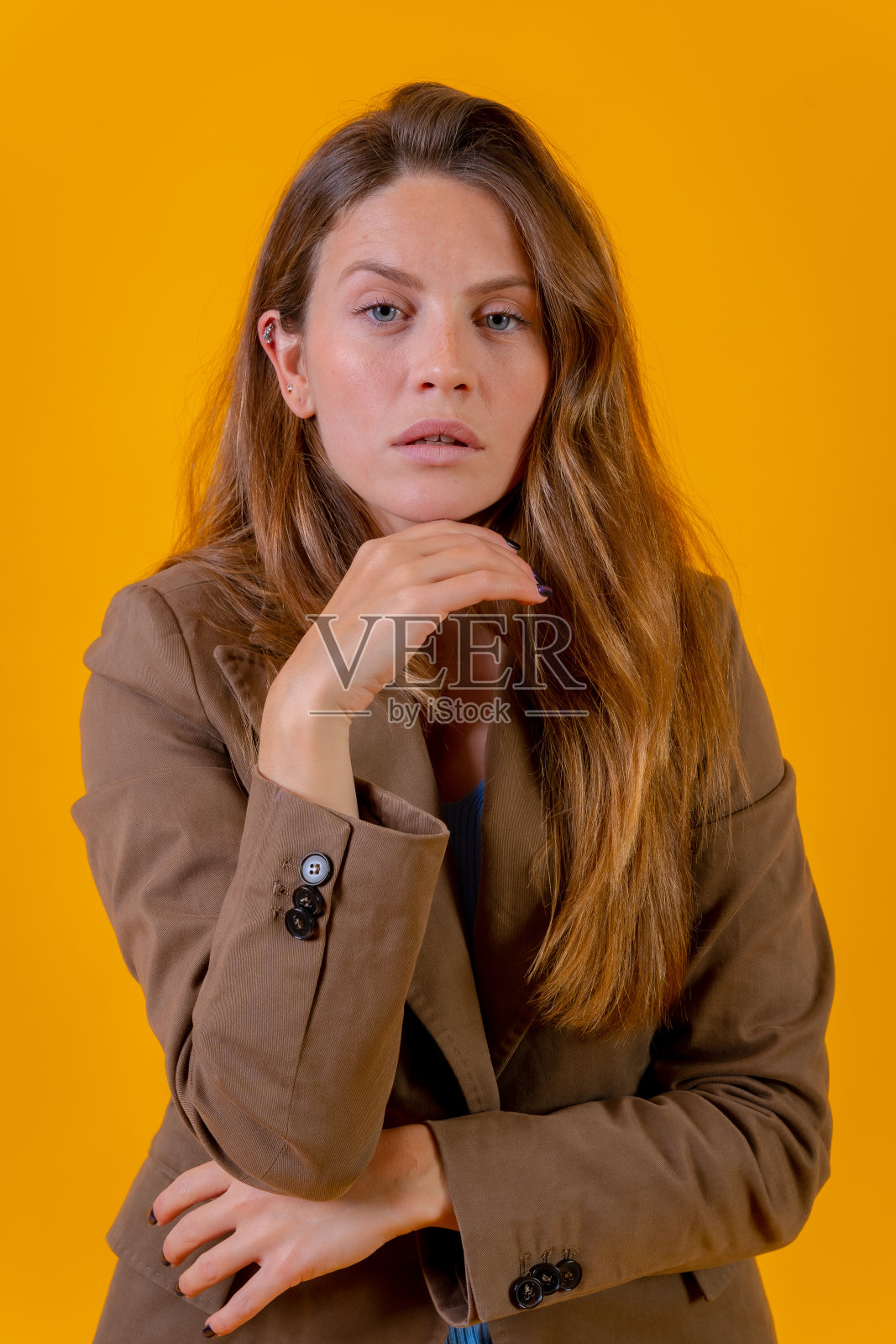 有吸引力的蓝眼睛女人的肖像在棕色夹克的黄色背景照片摄影图片