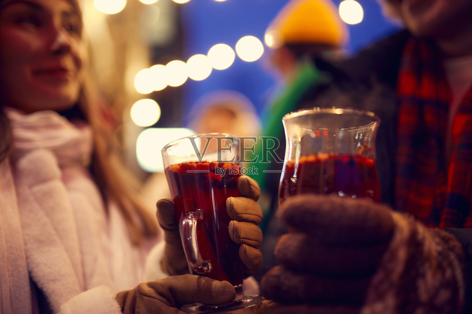 戴着连指手套的手和一杯热红酒的特写。节日快乐，国家传统，冬季街头集市，圣诞概念。照片摄影图片