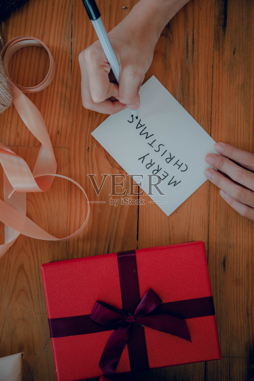 一位女士在圣诞礼品盒中央的手工纸上写字照片摄影图片