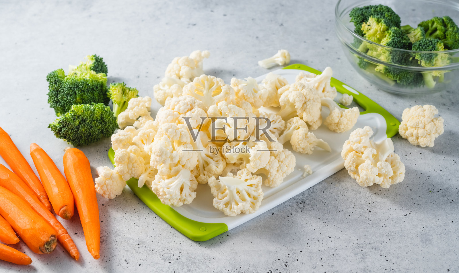 西兰花小花，花椰菜，胡萝卜特写。新鲜的生有机蔬菜放在厨房餐桌上的白色砧板上，静物照片摄影图片