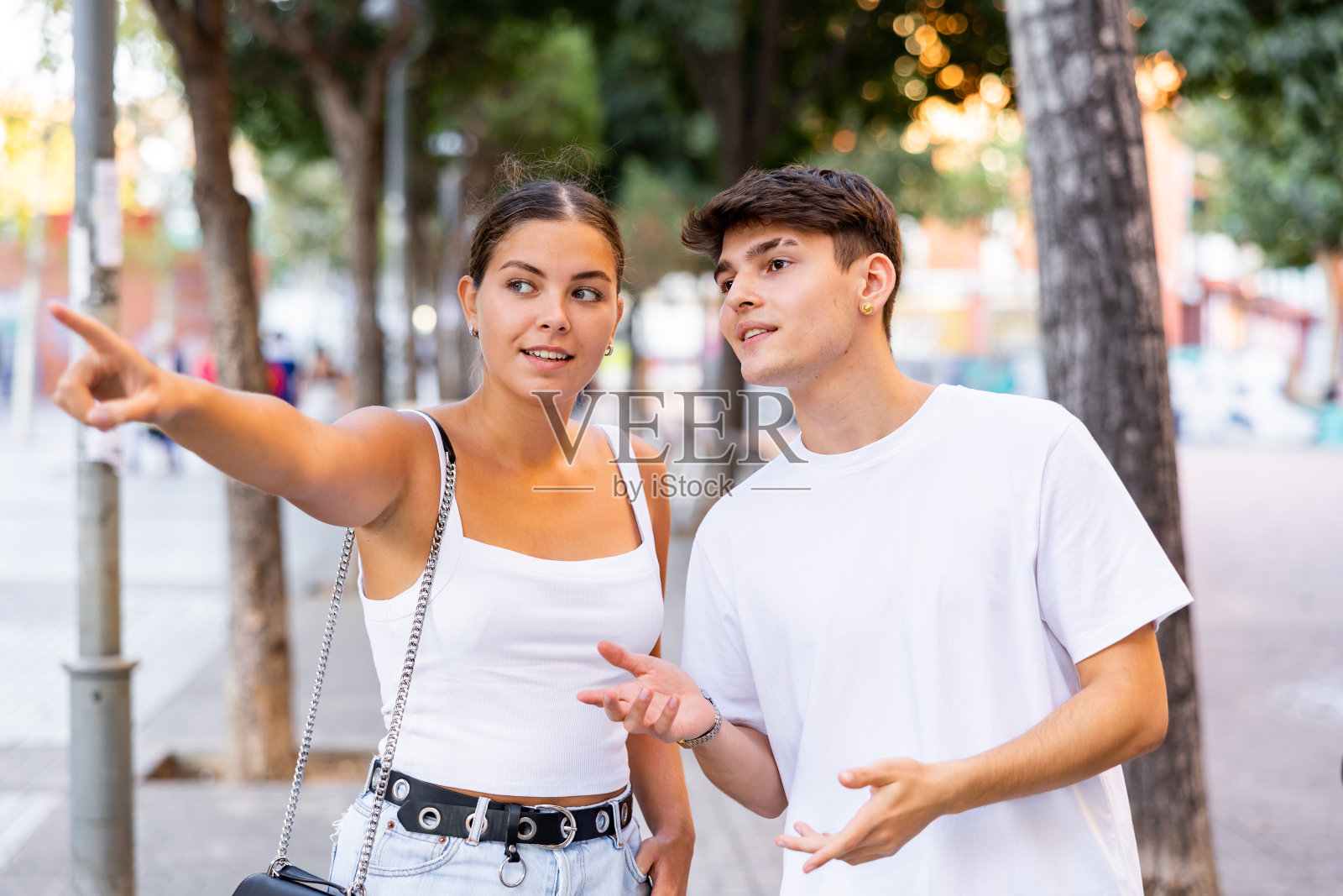 夏日，一对积极的游客情侣漫步在外国城市，指点着风景照片摄影图片