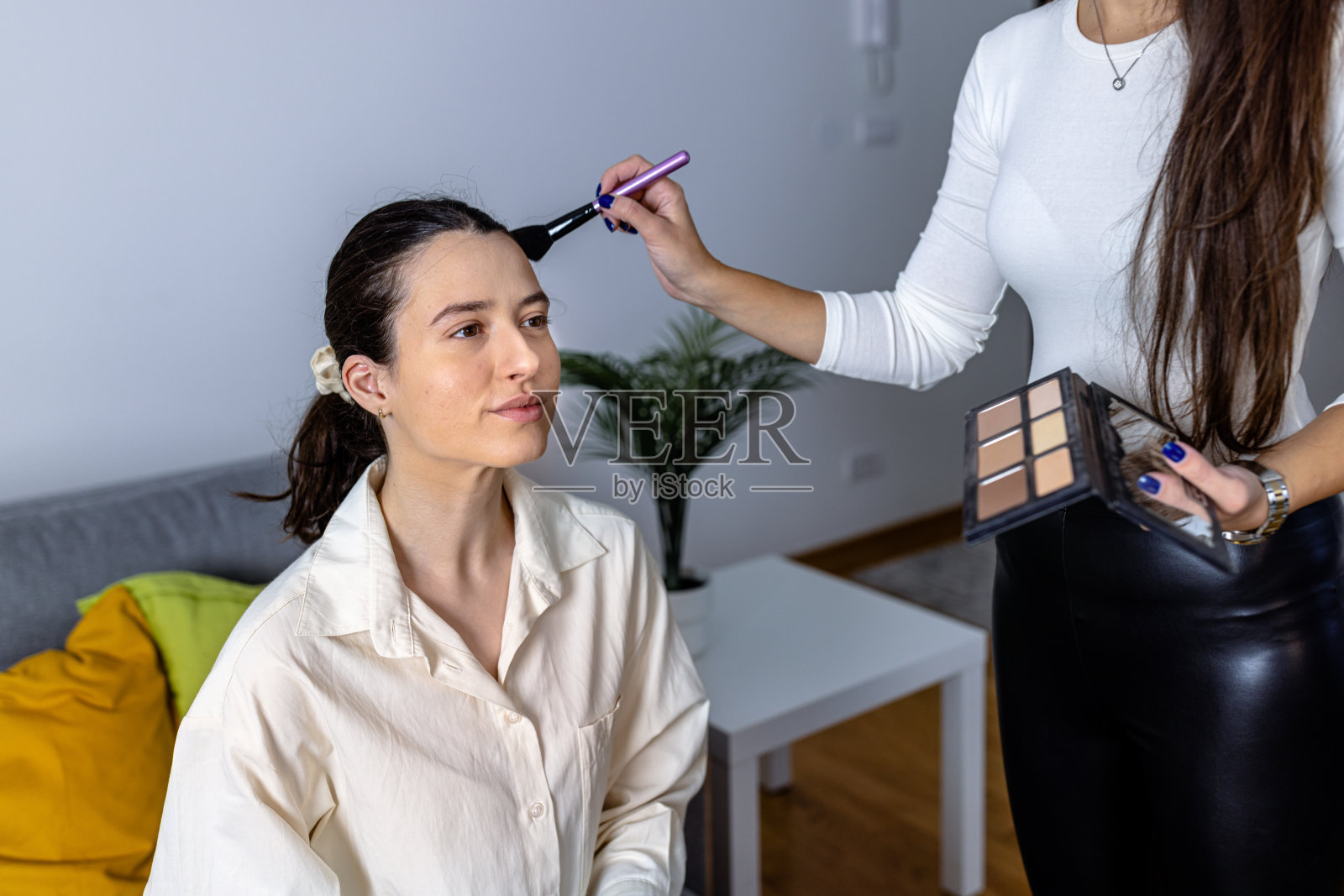 女化妆师用画笔纠正女性化妆的照片。照片摄影图片