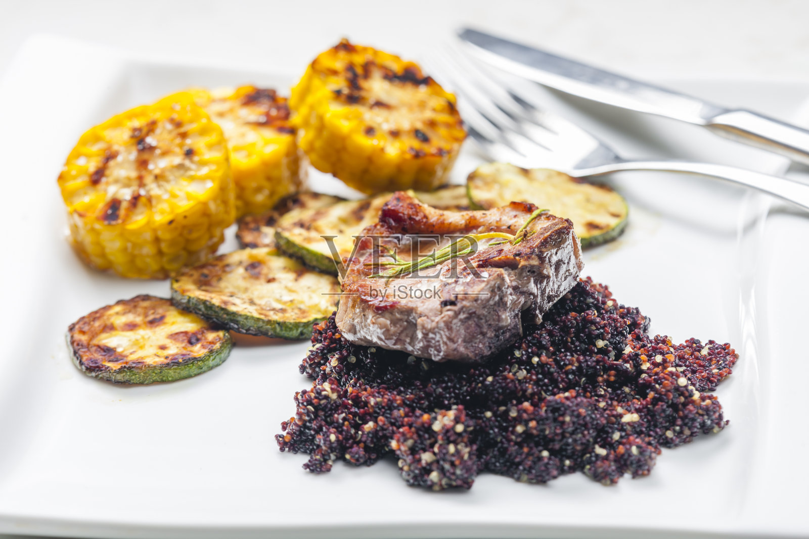 烤猪肉排配西葫芦和玉米配黑藜麦照片摄影图片