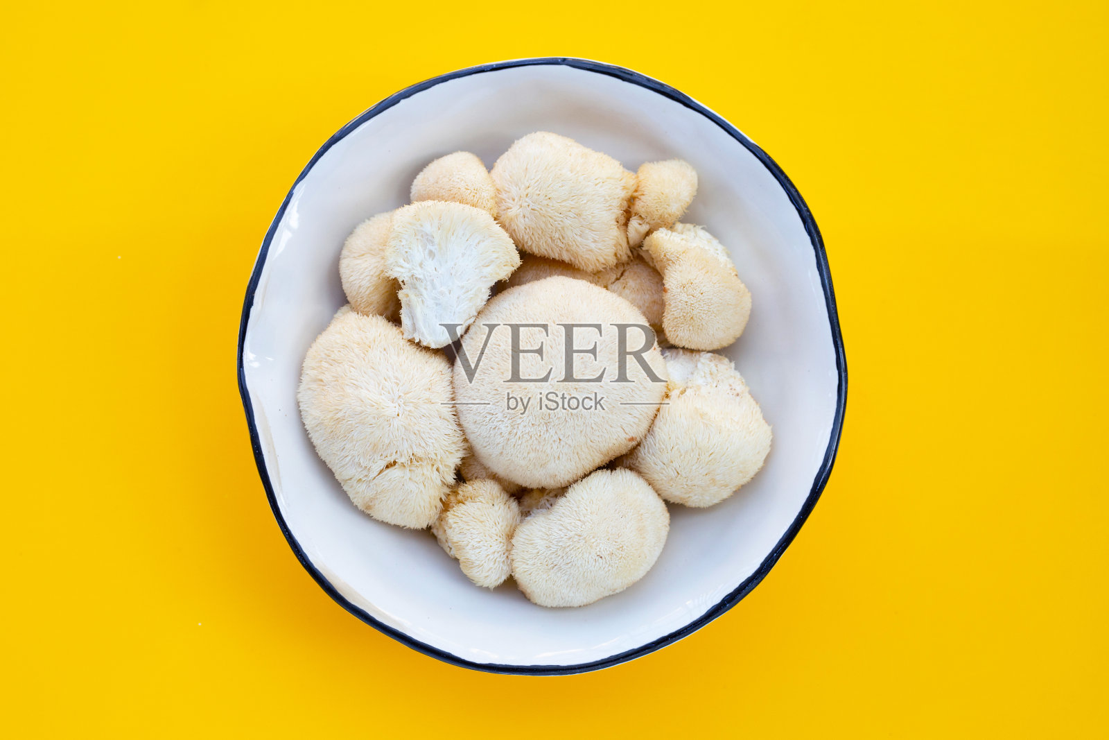 新鲜的狮子鬃毛蘑菇在黄色背景。照片摄影图片