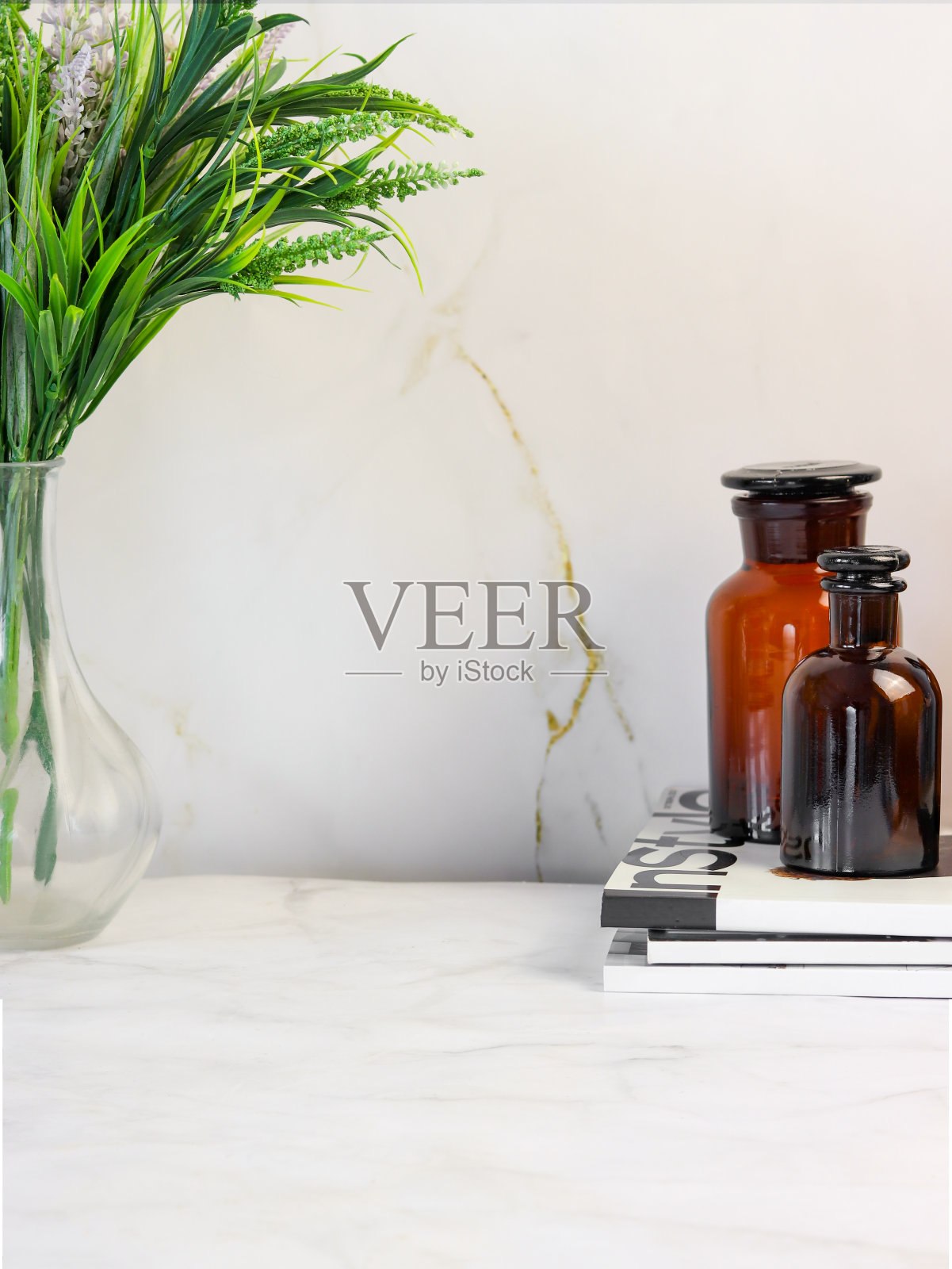 大理石背景上立着棕色玻璃瓶，花瓶里插着一束绿色植物。背景。Copyspace照片摄影图片