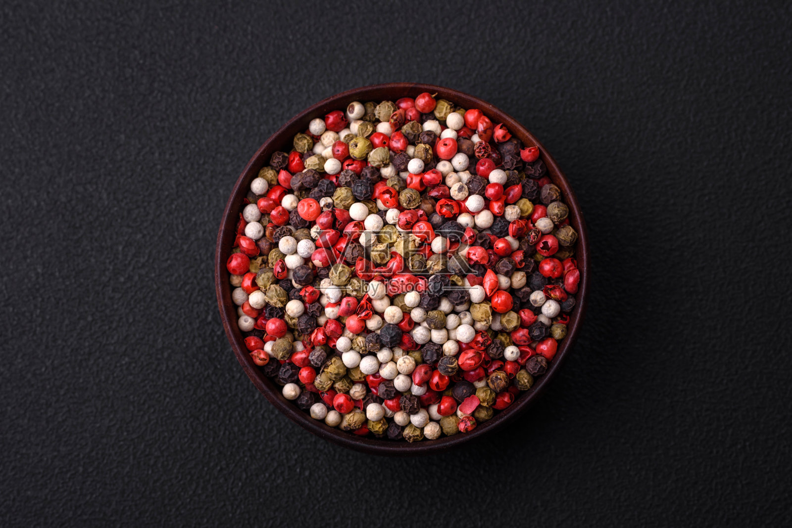 多香豌豆装在木碗里，背景是黑色混凝土照片摄影图片