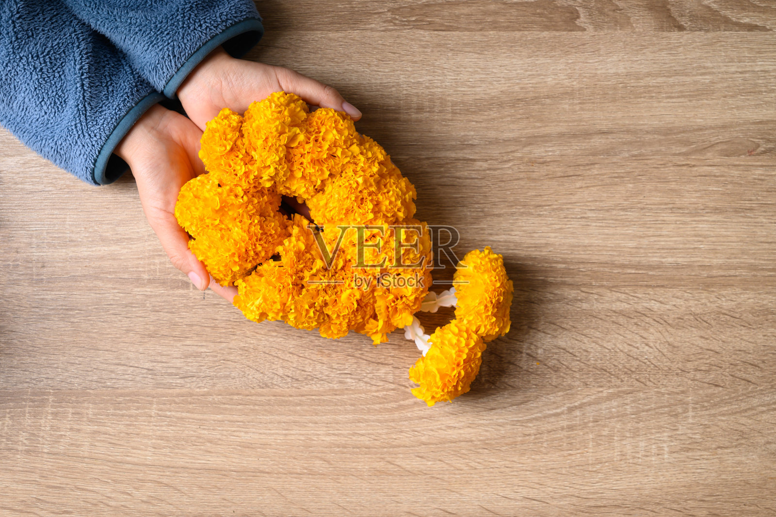 黄色的金盏花花环在手的木制背景，精神的花照片摄影图片