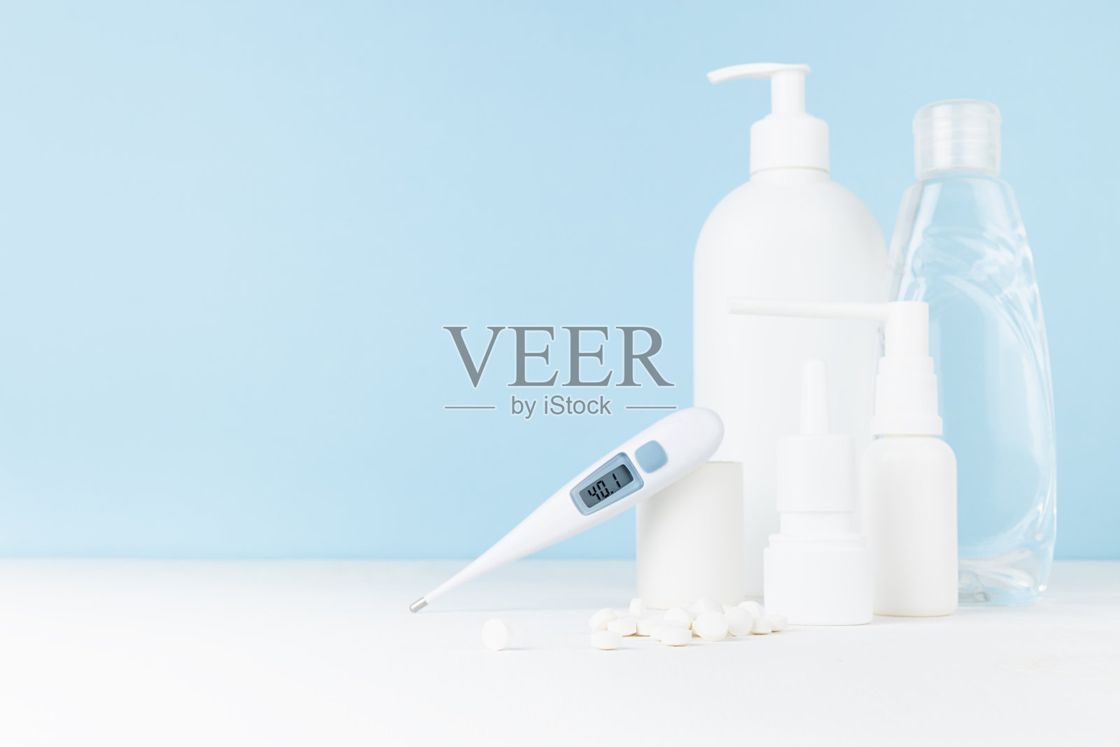 医疗和治疗药物-用于预防、治疗疾病、流感、普通感冒、病毒的白色瓶子- 40,1发热温度计，喷雾剂，药片，白色桌子上的消毒剂，蓝色墙壁，复制空间。照片摄影图片