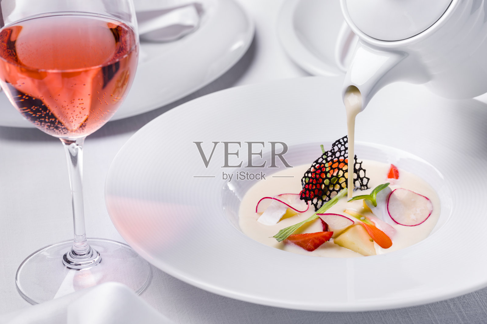 汤里有奶酪、韭菜、蘑菇、绿豆沙拉、萝卜、蕾丝片和草莓，盘子里放着一杯酒照片摄影图片