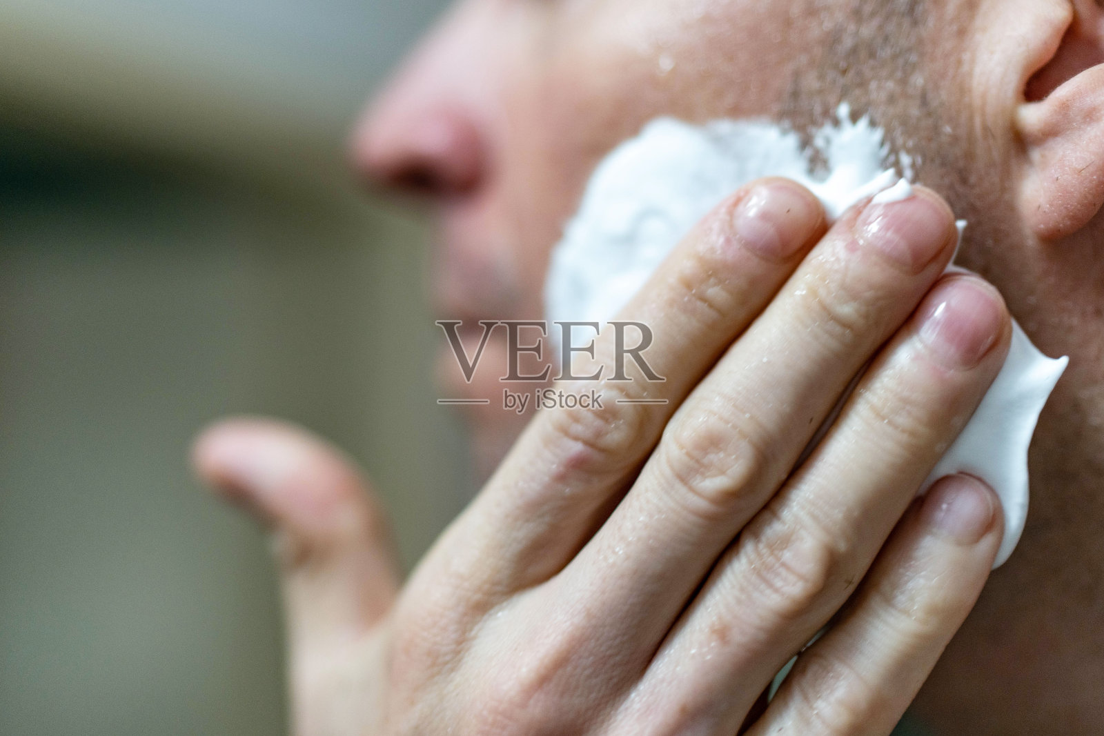一名年轻男子在家里的浴室里把剃须膏涂在脸上照片摄影图片