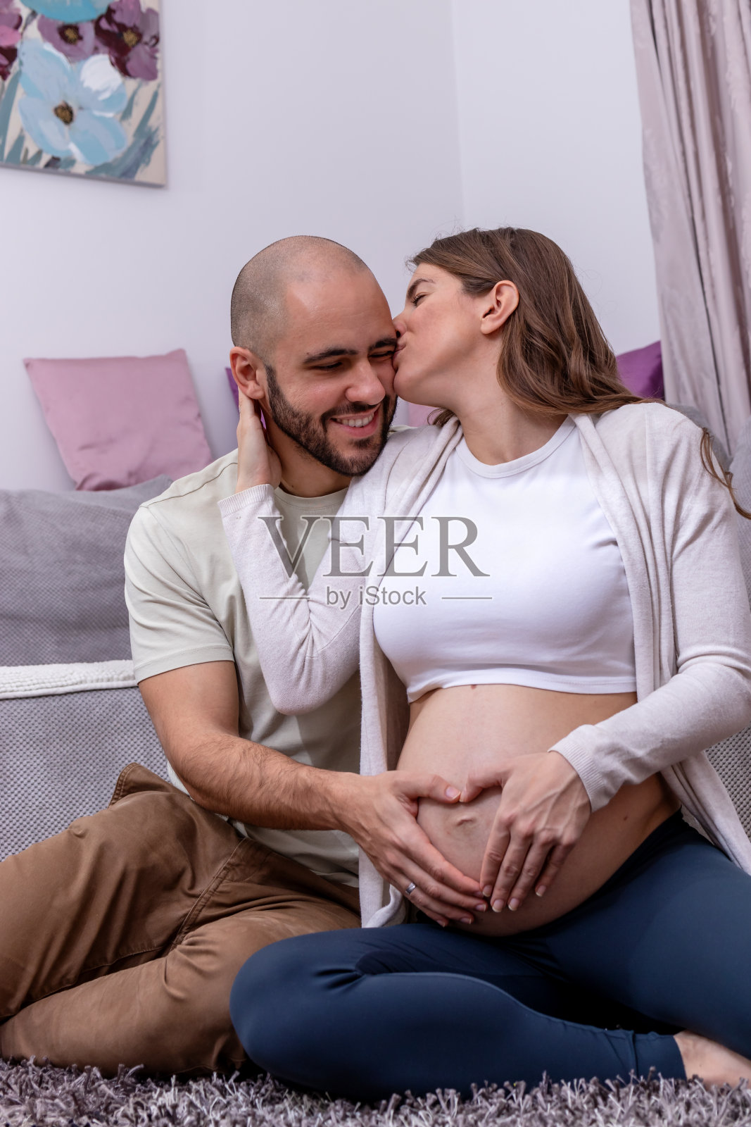 一对幸福的年轻夫妇坐在地板上，准备分娩。照片摄影图片