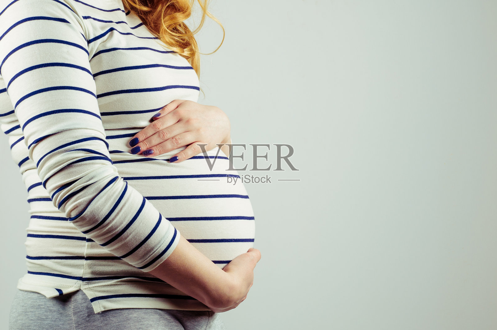 怀孕的女孩抱着她的肚子照片摄影图片