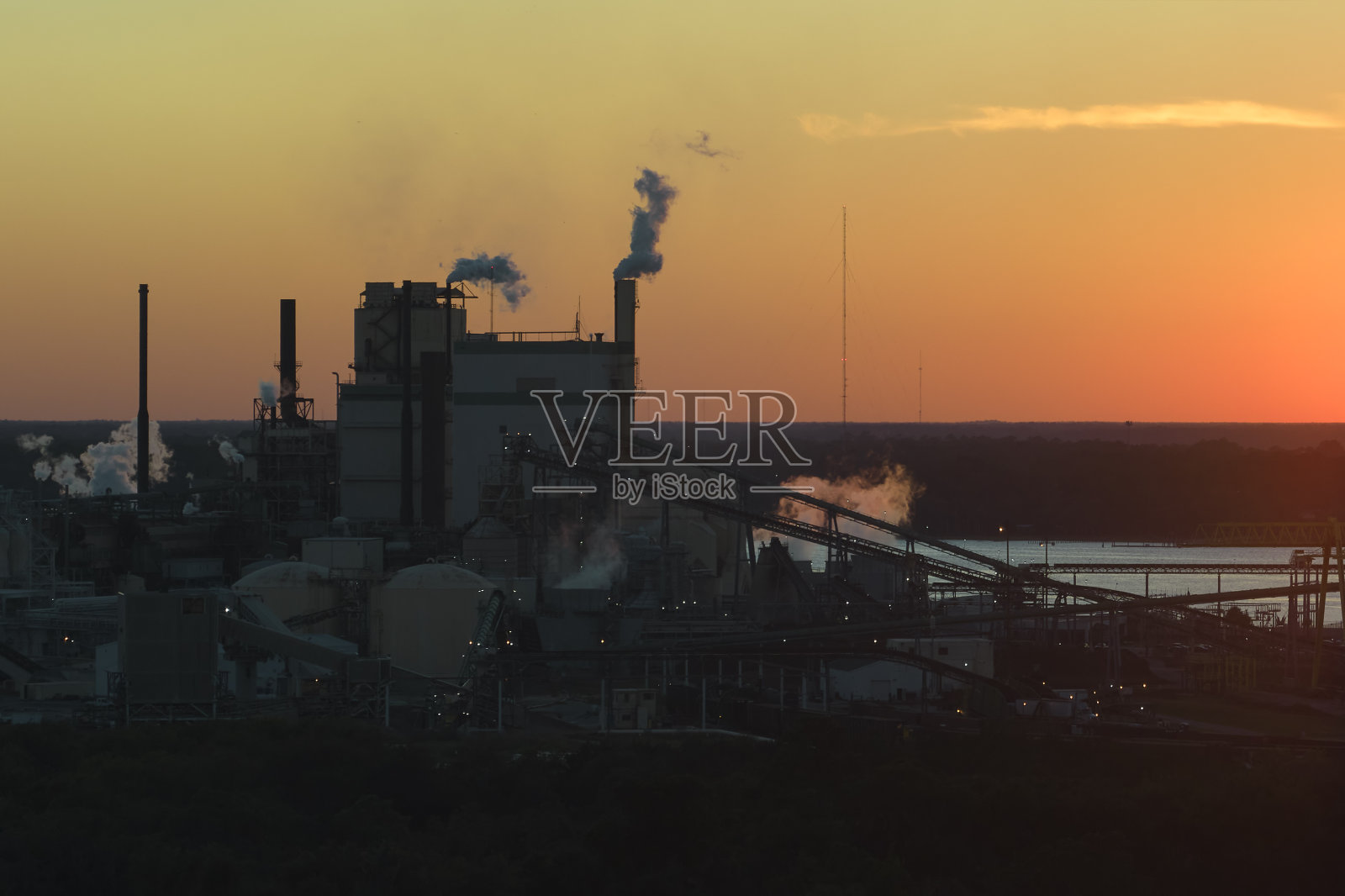 木材加工厂鸟瞰图，生产过程产生的烟雾污染了工厂制造场地的大气。日落时分的工业现场照片摄影图片