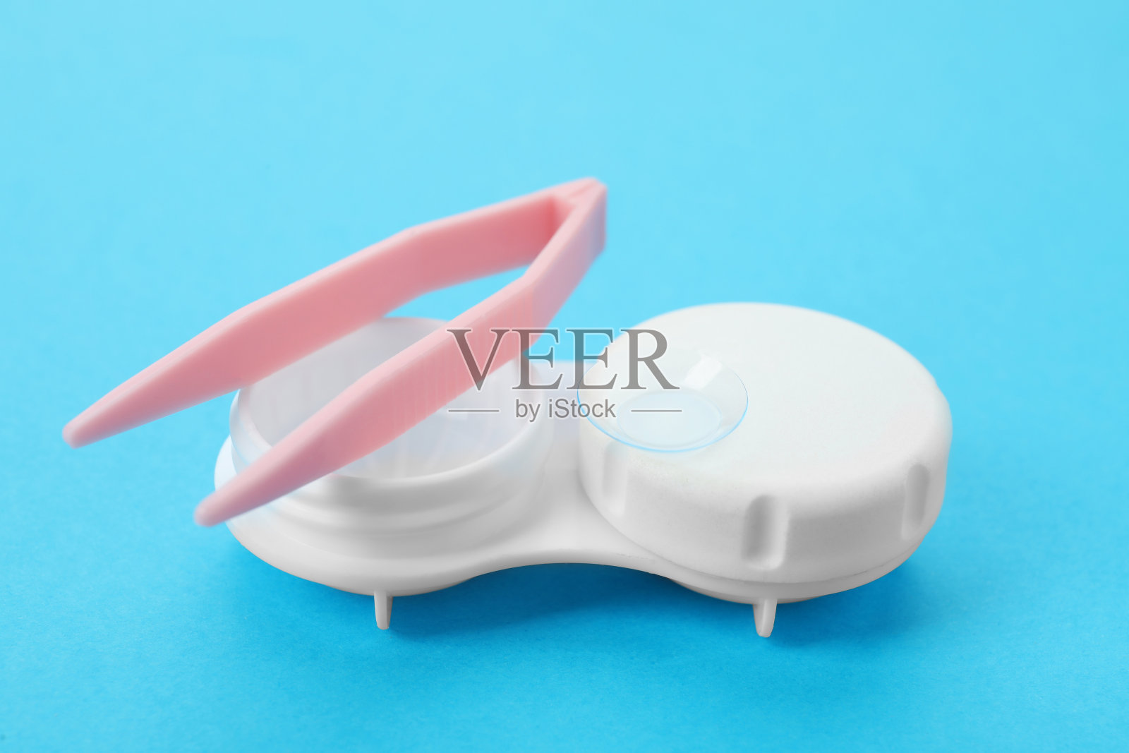 浅蓝色背景上的隐形眼镜和镊子，特写照片摄影图片