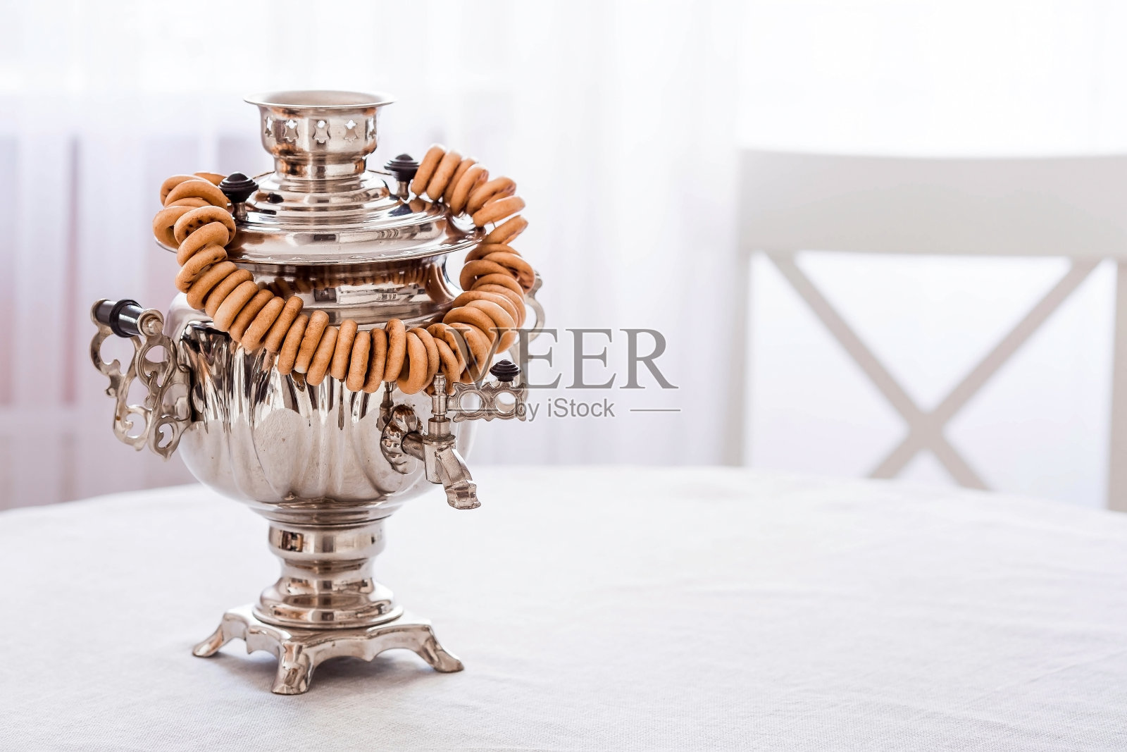 俄罗斯的传统。用茶炊喝茶。在现代白色厨房里，有百吉饼、干果和俄罗斯茶炊的静物。照片摄影图片