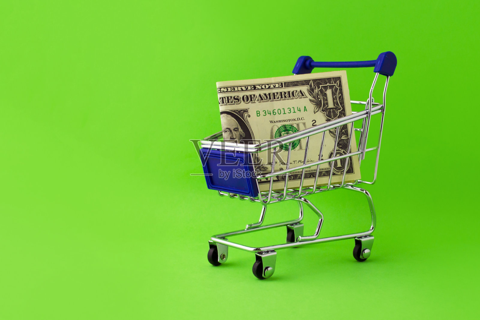 绿色背景上印有1美元钞票的购物车。照片摄影图片