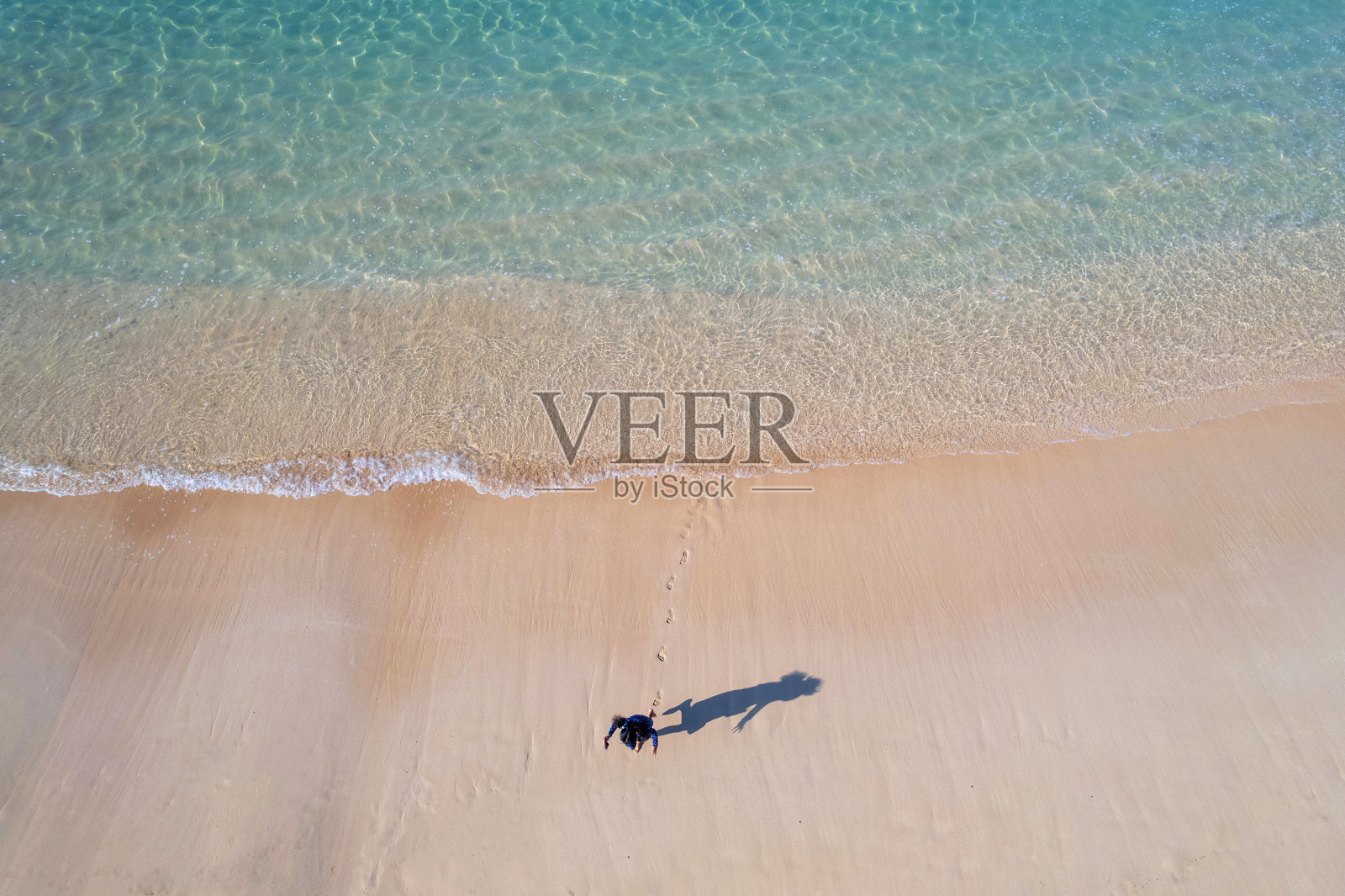 无人机的女孩和她的影子玩在一个晶莹剔透的海滩照片摄影图片