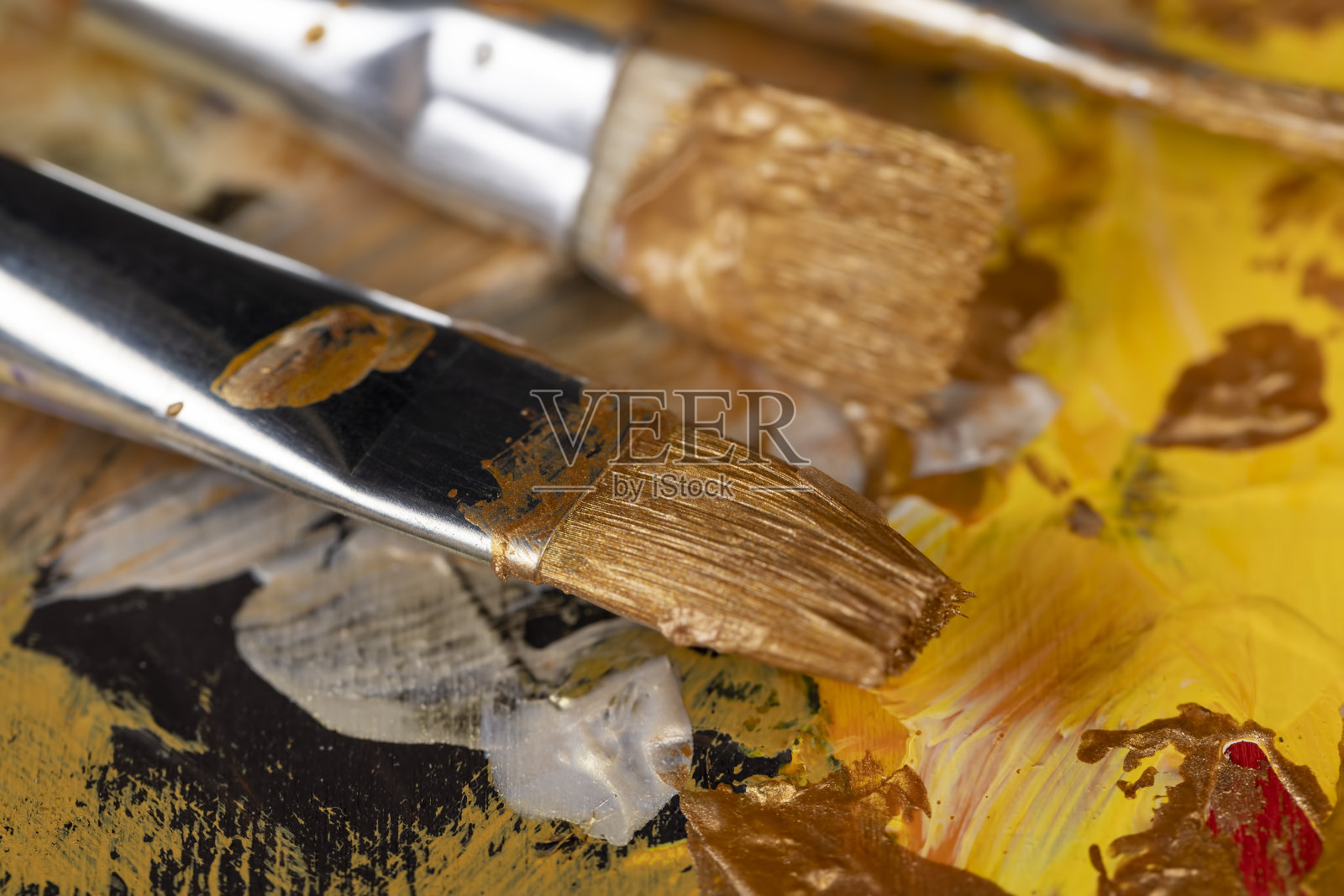 用艺术画笔在画布上用金色颜料作画照片摄影图片