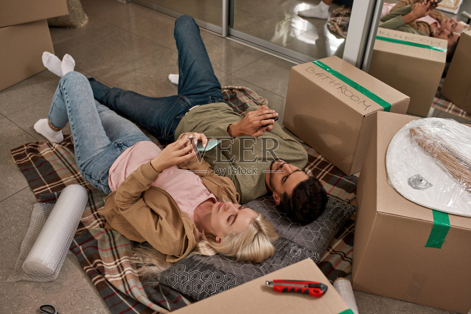 年轻夫妇在地板上的毯子上使用智能手机照片摄影图片