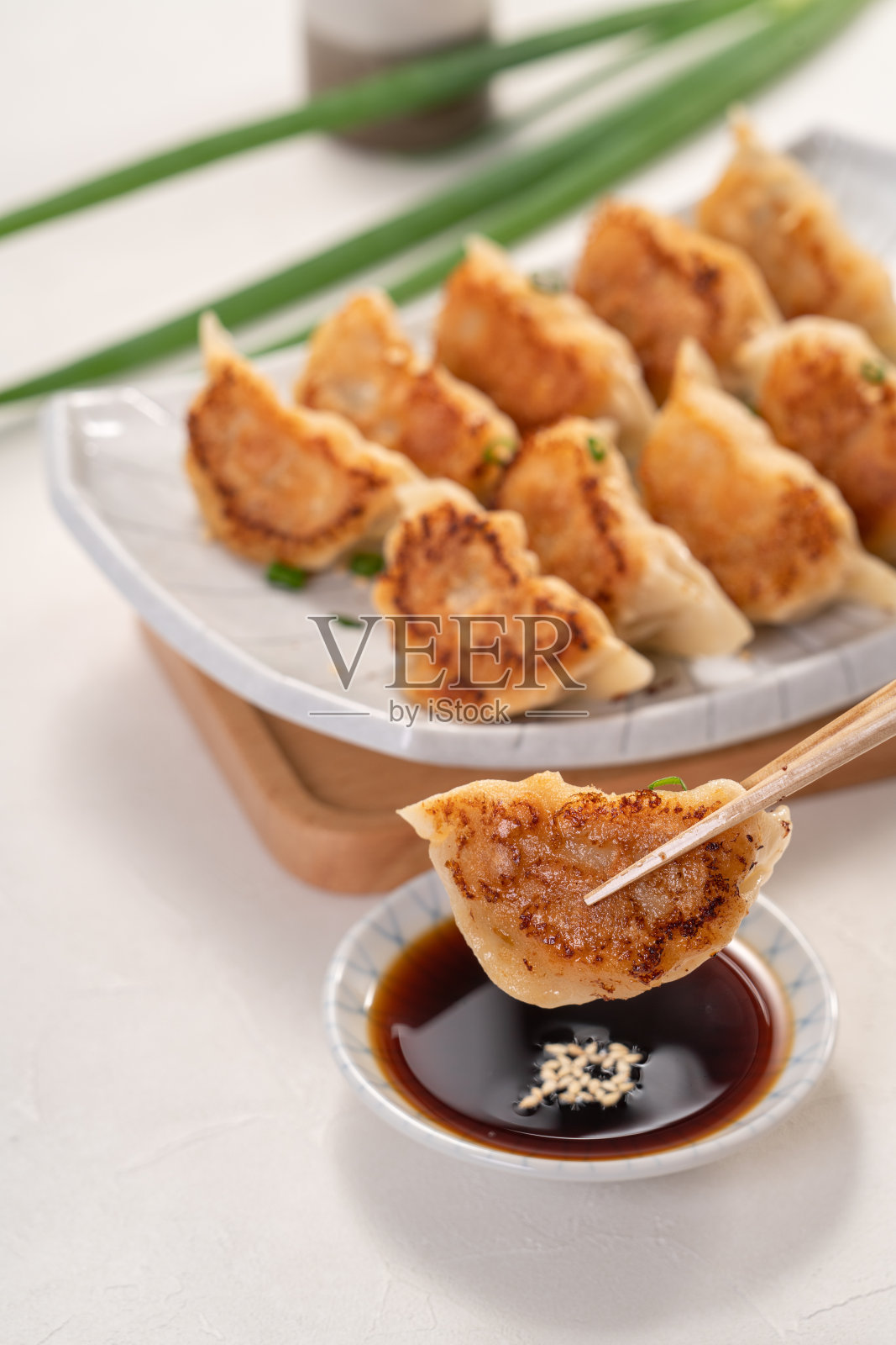 平底锅煎饺子饺子在盘子与酱油在白色的桌子背景。照片摄影图片