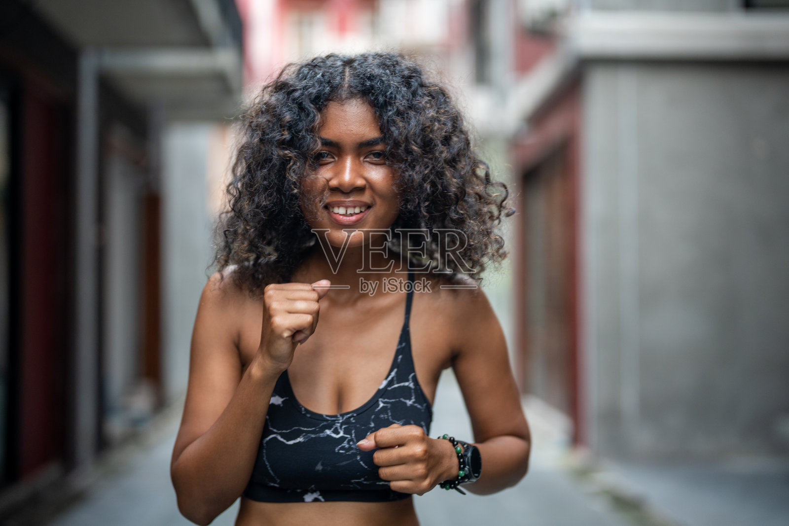 有吸引力和强大的非洲女人在户外城市健身前伸展。体育的概念。健康的生活方式。女人通过空中拳击热身。照片摄影图片