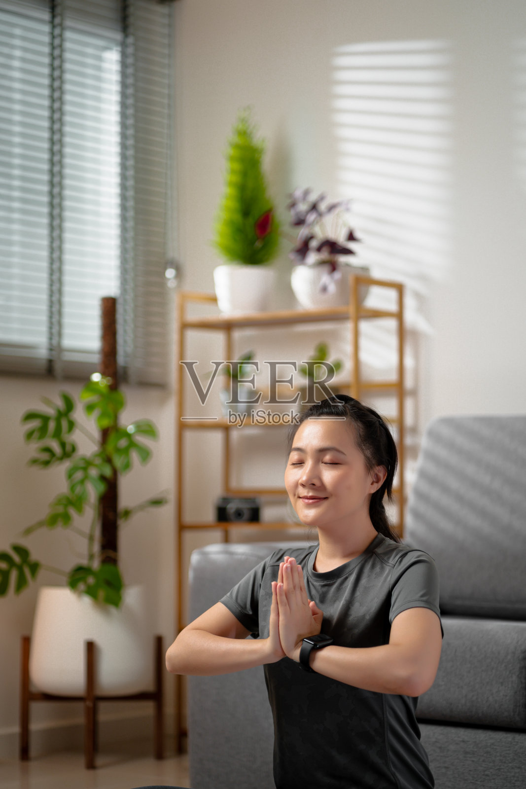亚洲妇女盘腿坐在垫子上瑜伽练习的祈祷姿势在家里的客厅。照片摄影图片