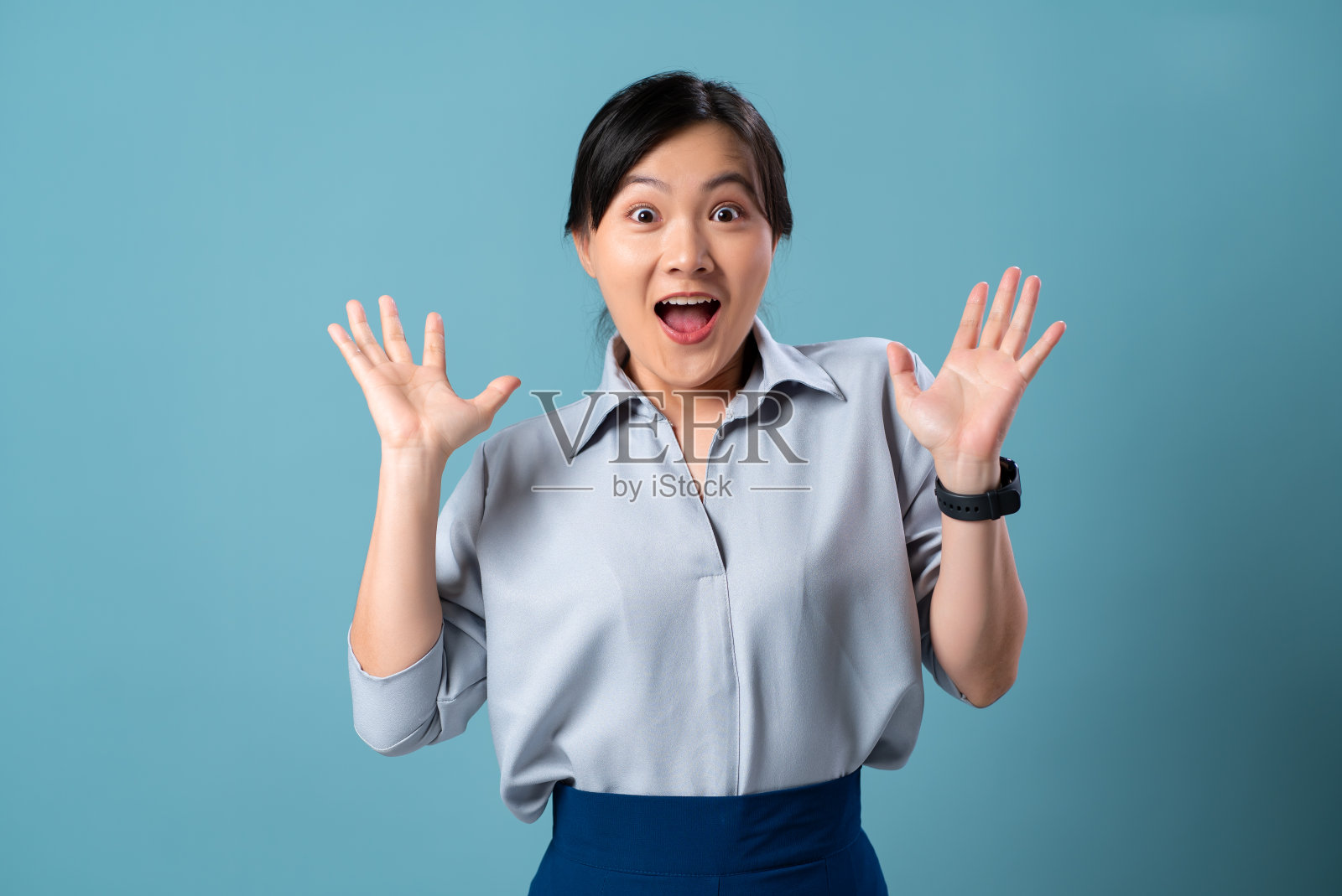 亚洲妇女高兴，微笑，兴奋，看着相机孤立在蓝色的背景。照片摄影图片