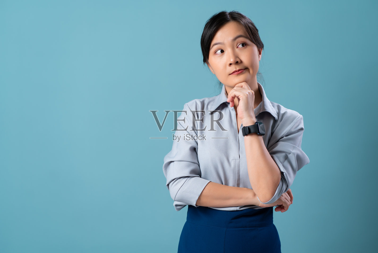 亚洲妇女思考，担心和困惑孤立地站在蓝色背景。照片摄影图片