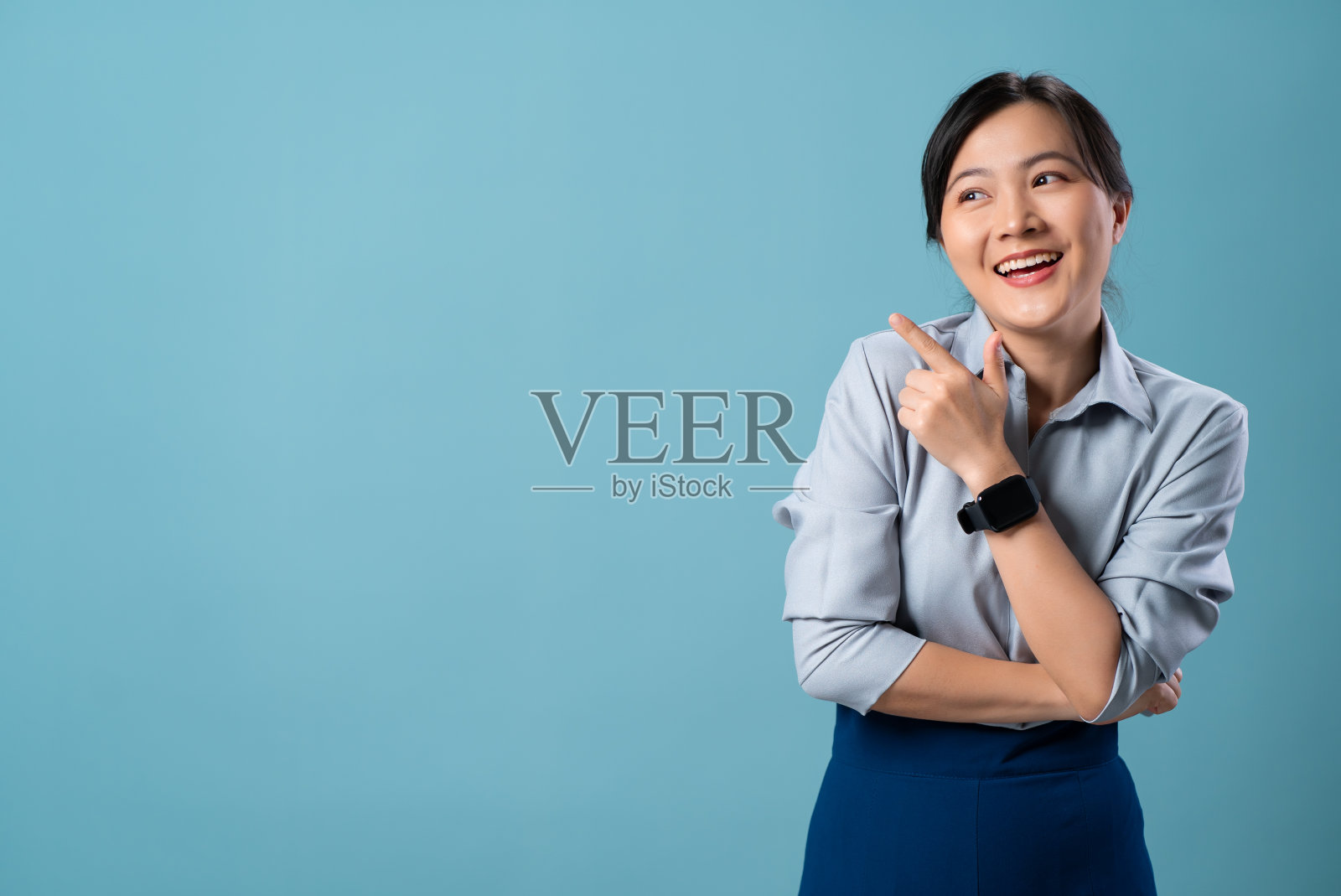 亚洲妇女快乐的微笑显示和看着空白复制空间孤立在蓝色背景。照片摄影图片