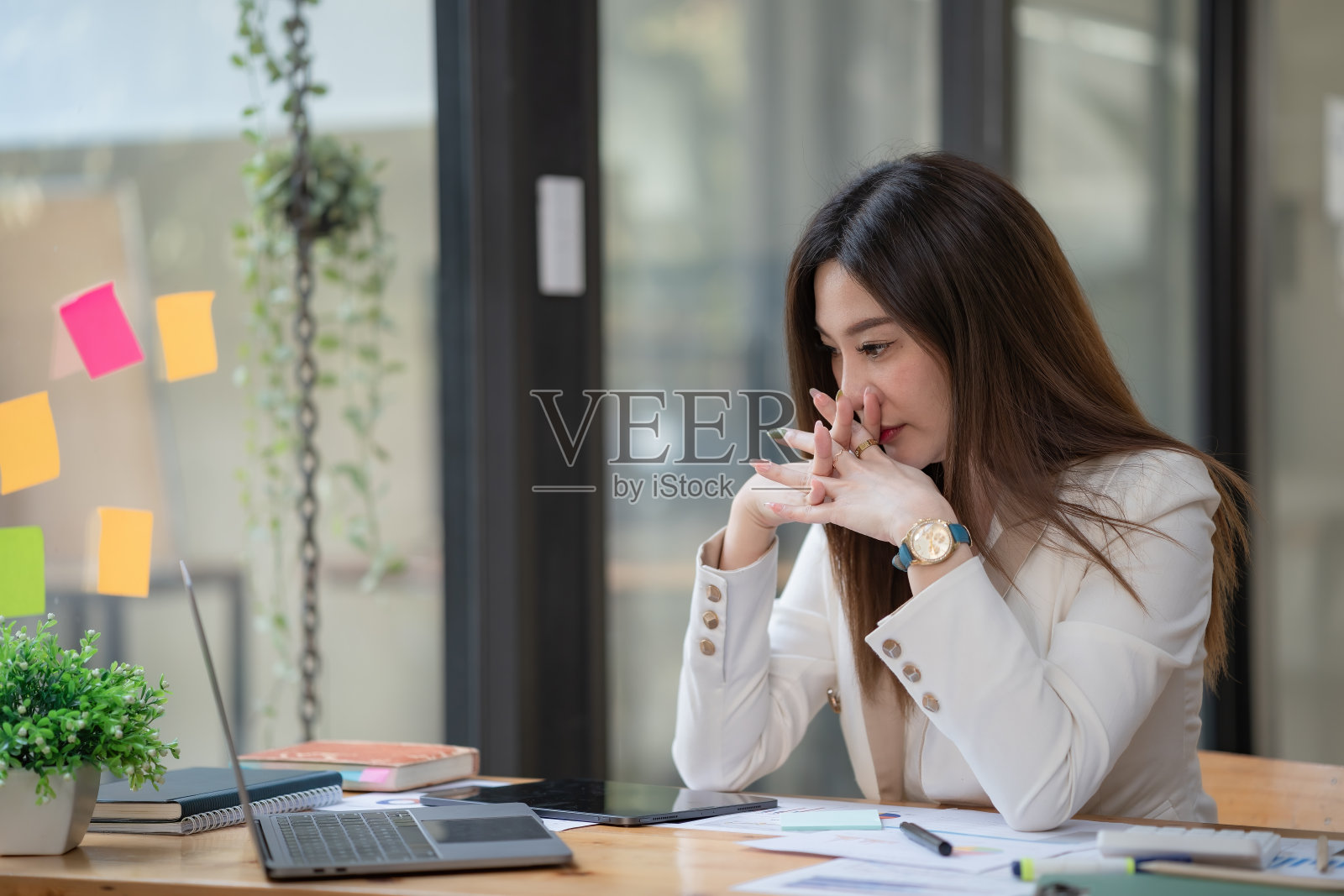 压力大的年轻女商人头痛在办公室用笔记本电脑工作。照片摄影图片