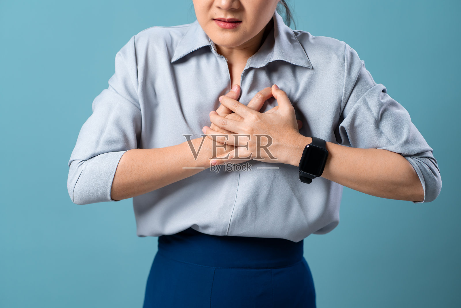 特写镜头的妇女有严重的胸痛孤立地站在蓝色背景。照片摄影图片
