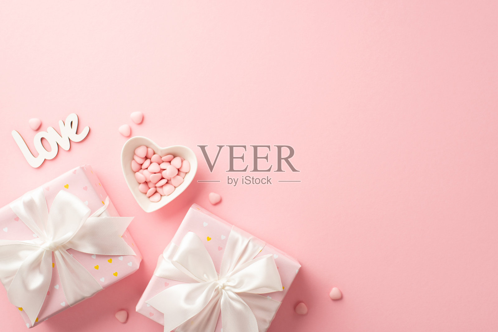 情人节的概念。顶部视图照片的礼物盒与白色丝带蝴蝶结心形碟子洒和铭文爱在孤立的粉彩粉红色背景与复制空间照片摄影图片