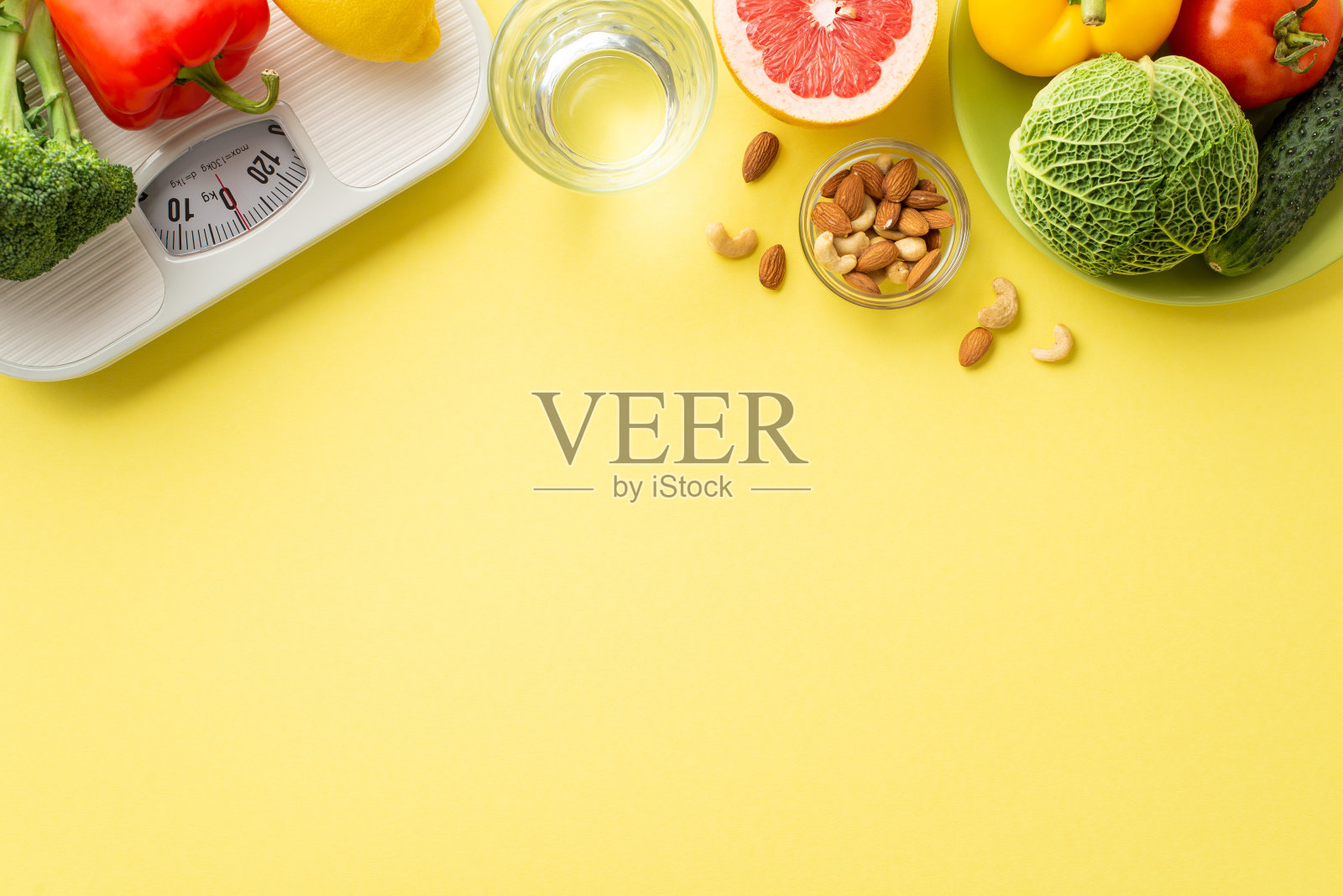 排毒的概念。顶部视图照片盘子与水果和蔬菜杏仁腰果玻璃水和鳞片在孤立的淡黄色背景与复制空间照片摄影图片