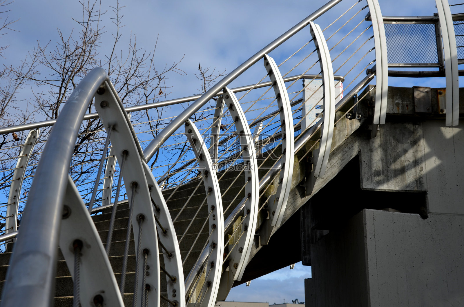 楼梯和宽阔的人行天桥，带穿孔金属地板。带圆孔的镀锌金属片。白色的栏杆像在拱门上的一艘船。扶手由抛光不锈钢管制成。照片摄影图片