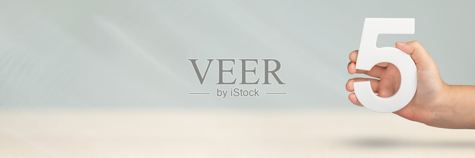 5号在手上。手握白色数字5在模糊的背景与复制空间。第五个概念。生日5岁，五年级，每周工作五天照片摄影图片