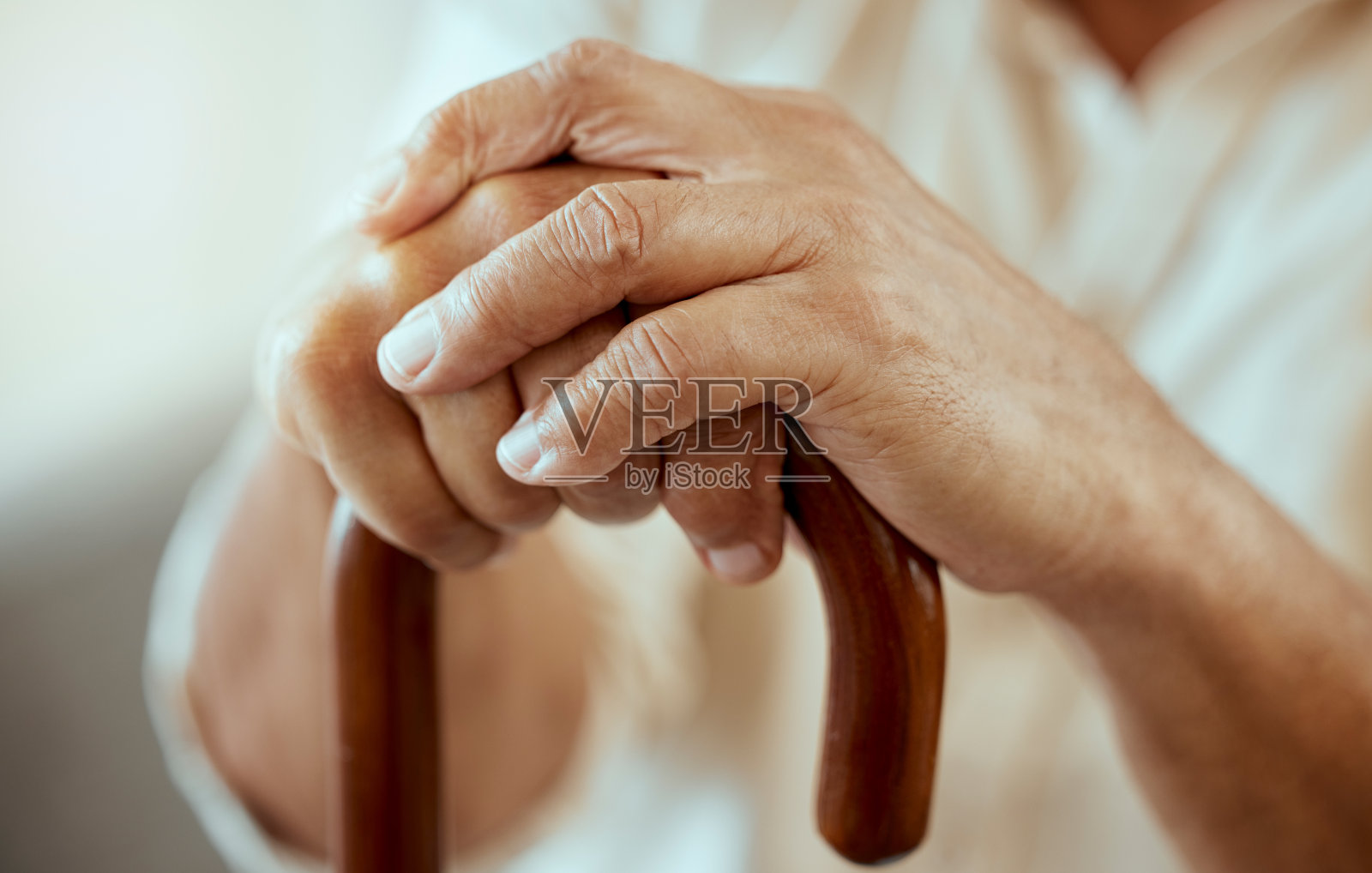 老人双手、手杖与残疾、退休与骨质疏松、关节炎与损伤。老年人、残疾人和老病人在养老院的支持、保健和病人帮助的木制拐杖照片摄影图片