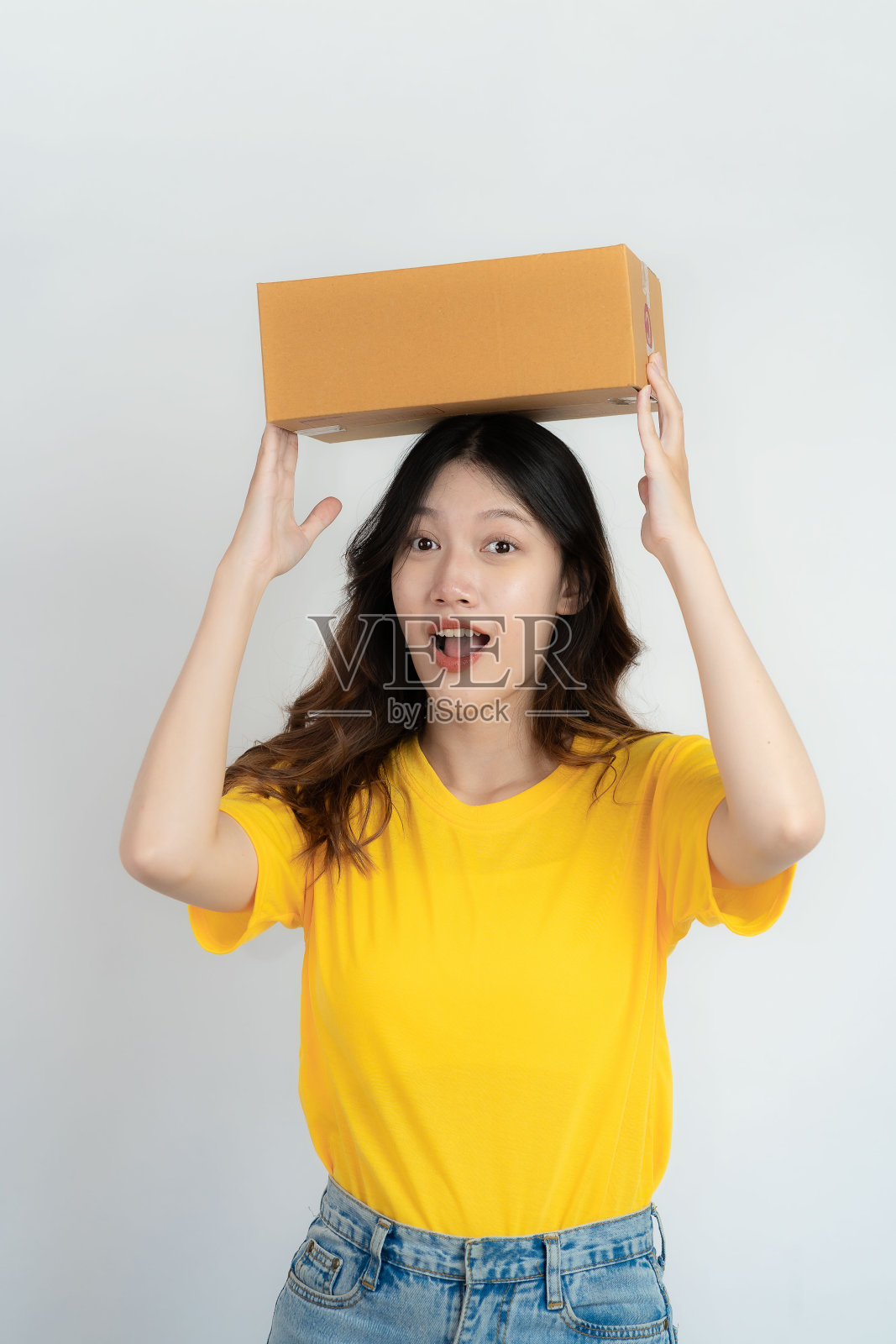 年轻的亚洲女子拿着一个盒子，带着迷人的微笑，孤立在白色的背景上。网上中小企业业务及配送理念。照片摄影图片