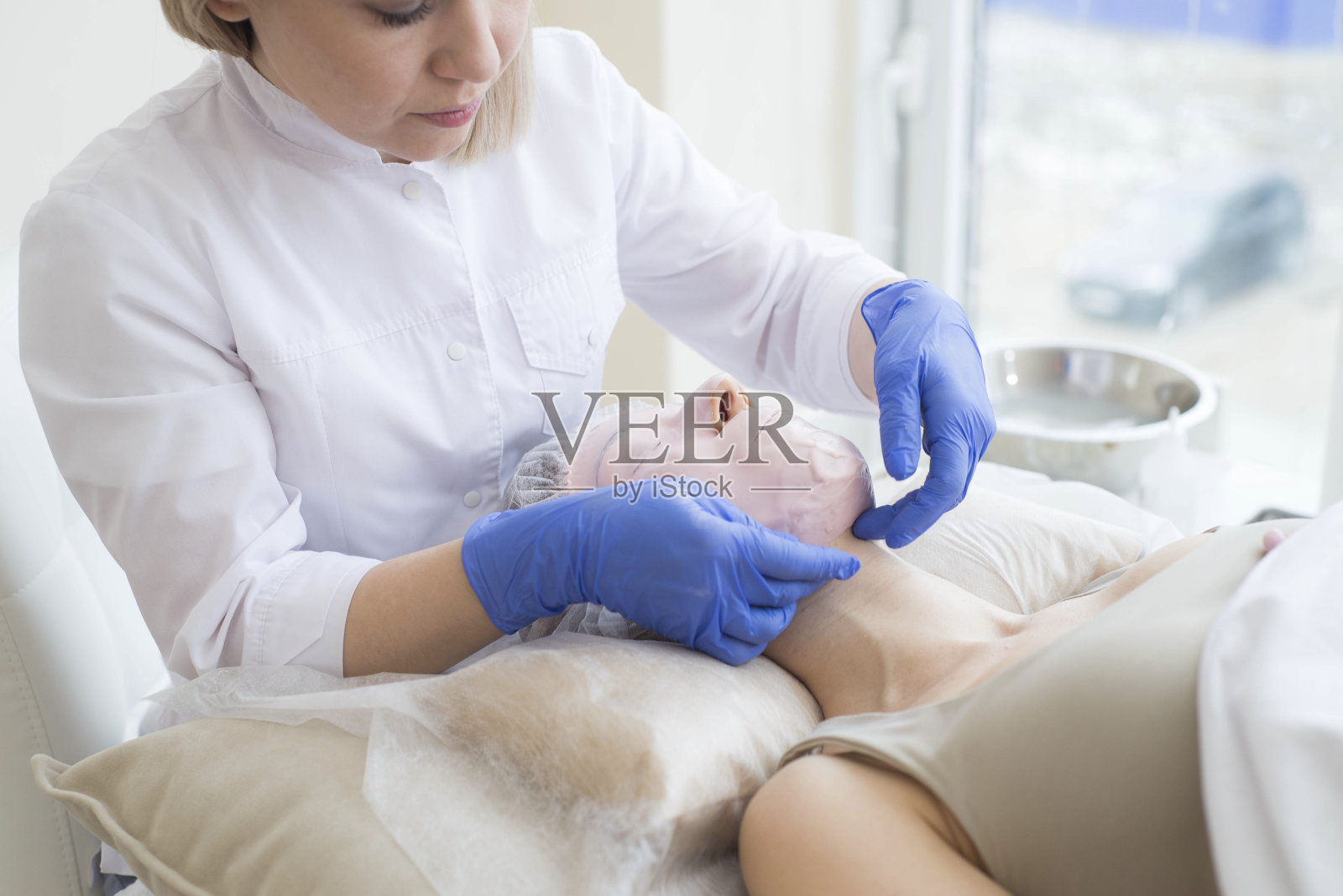 美容师在水疗中心从模特身上取下面具。照片摄影图片