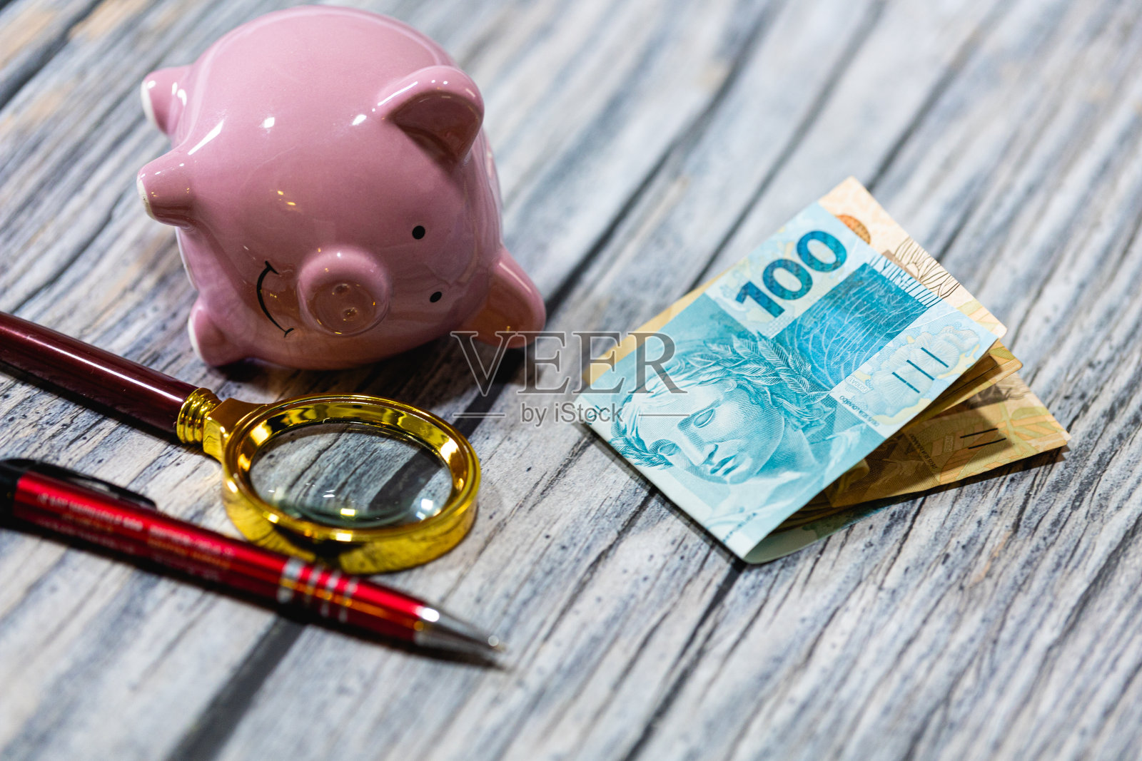 一张木桌上放着巴西雷亚尔钞票和一个存钱罐。巴西经济和金融。照片摄影图片