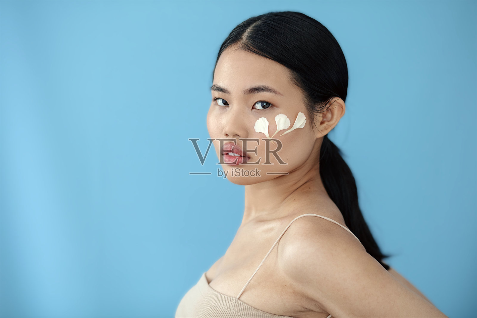 美丽的亚洲女人与花瓣在工作室摆姿势。照片摄影图片