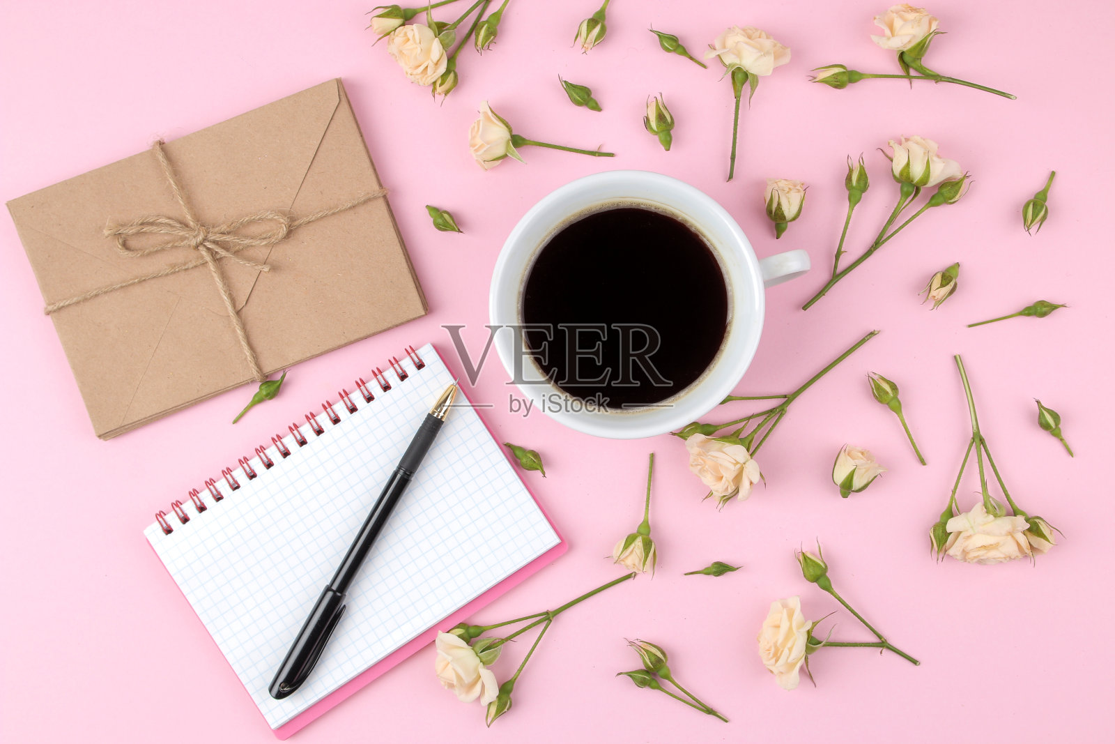 漂亮的迷你玫瑰，一杯咖啡和一个笔记本在明亮的粉红色背景。假期。情人节。妇女节。前视图。照片摄影图片