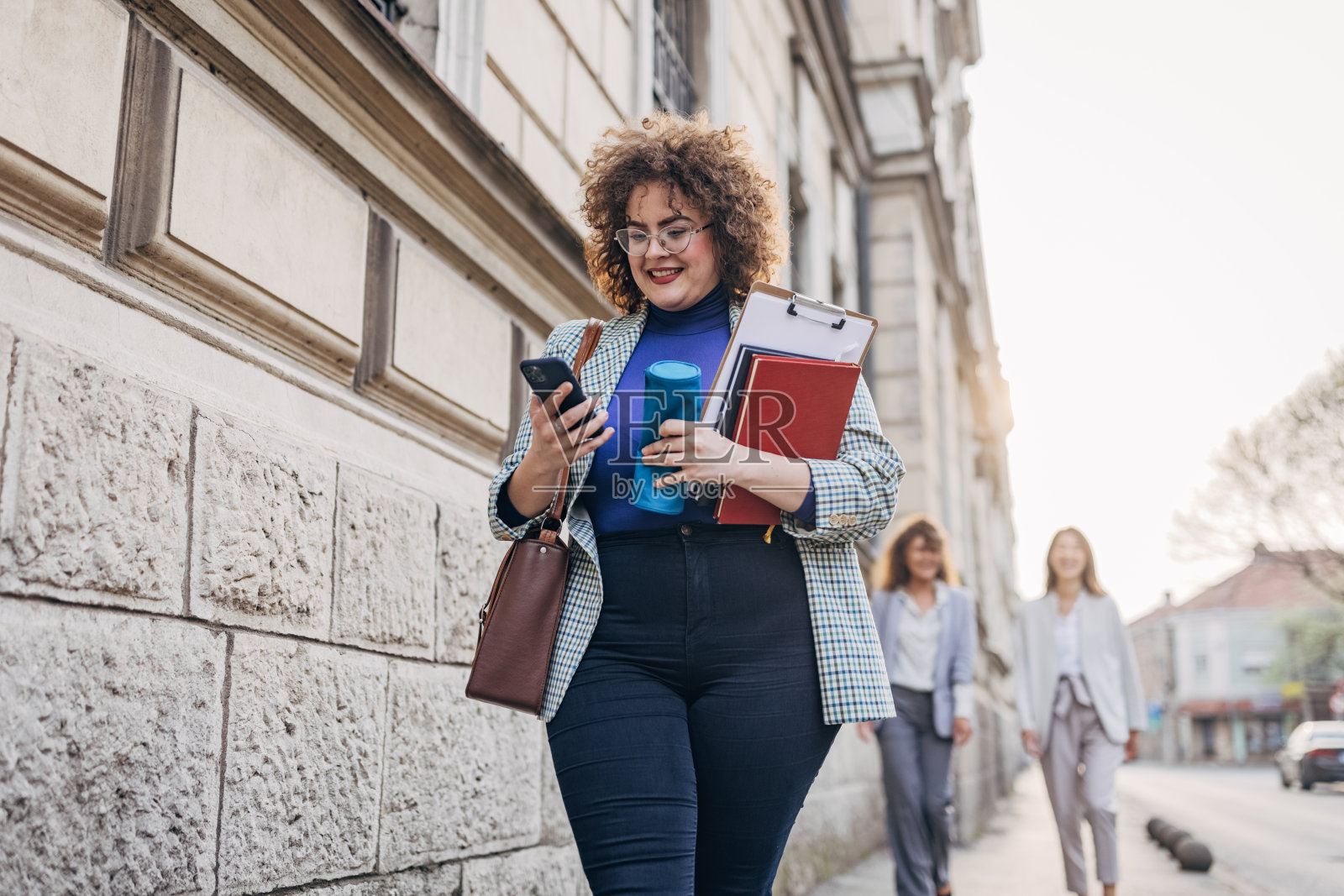 年轻女子一边走路一边用智能手机照片摄影图片